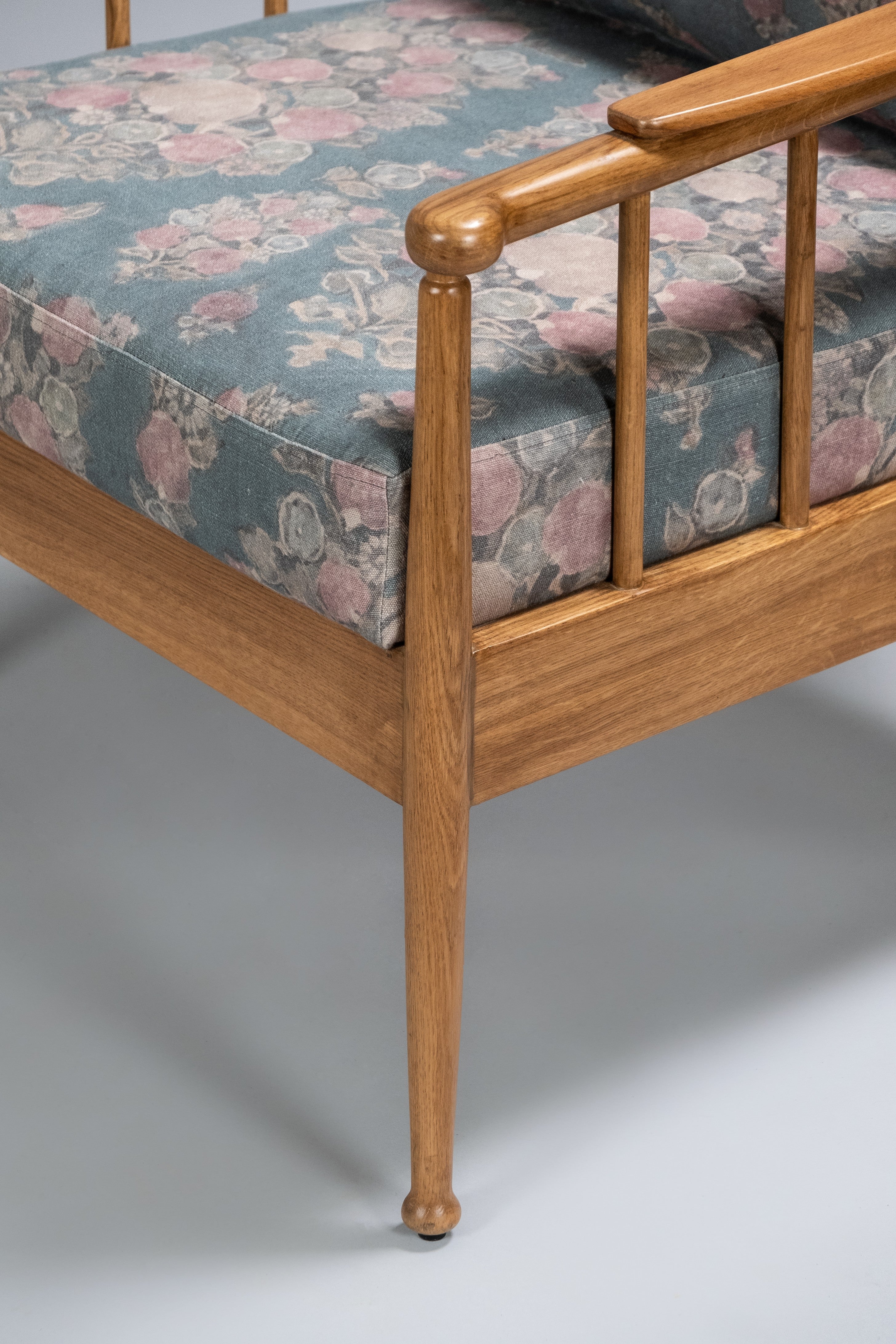 Wooden bed frame with floral mattress cover on a plain background