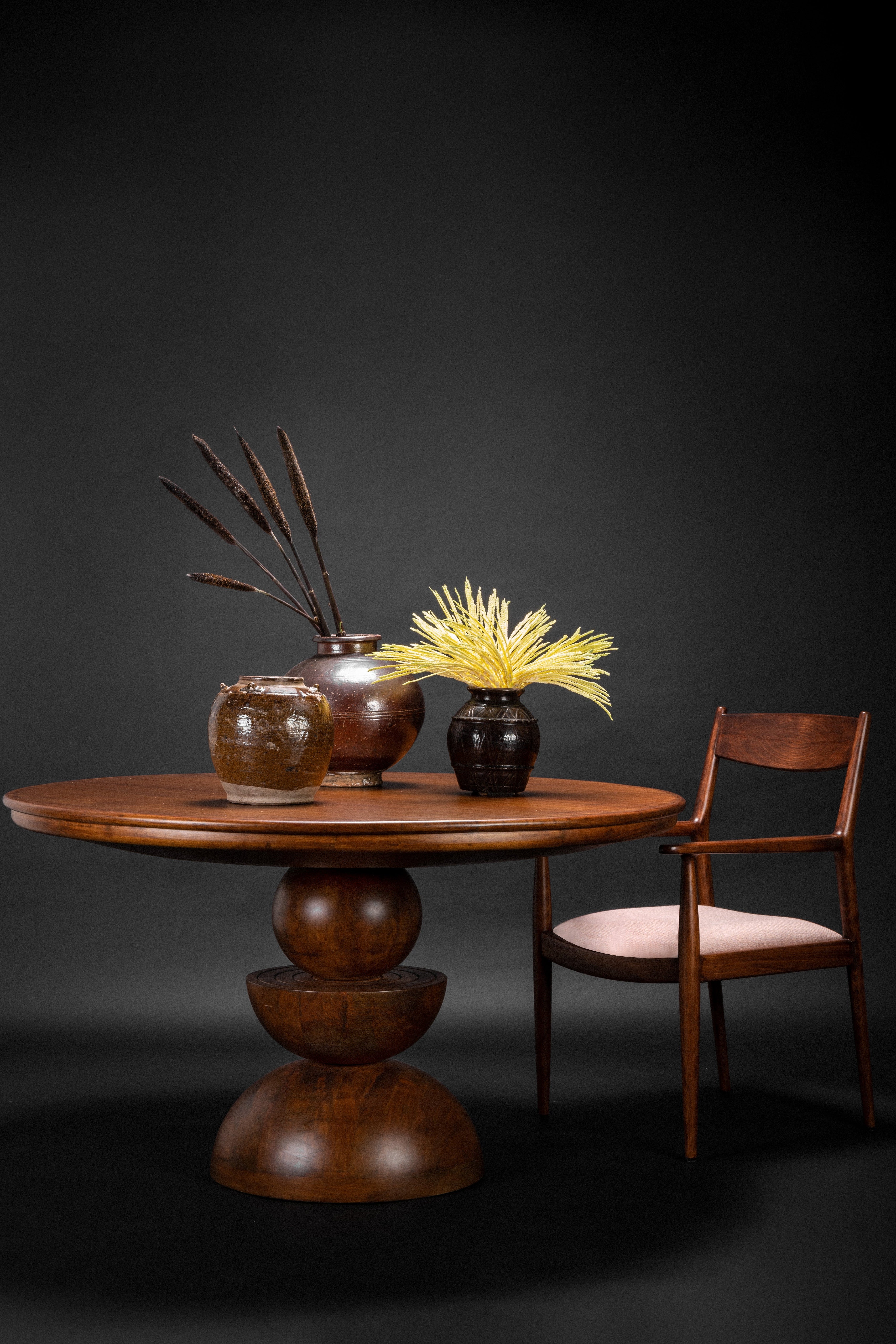 Wooden table with decorative items and a chair against a dark background
