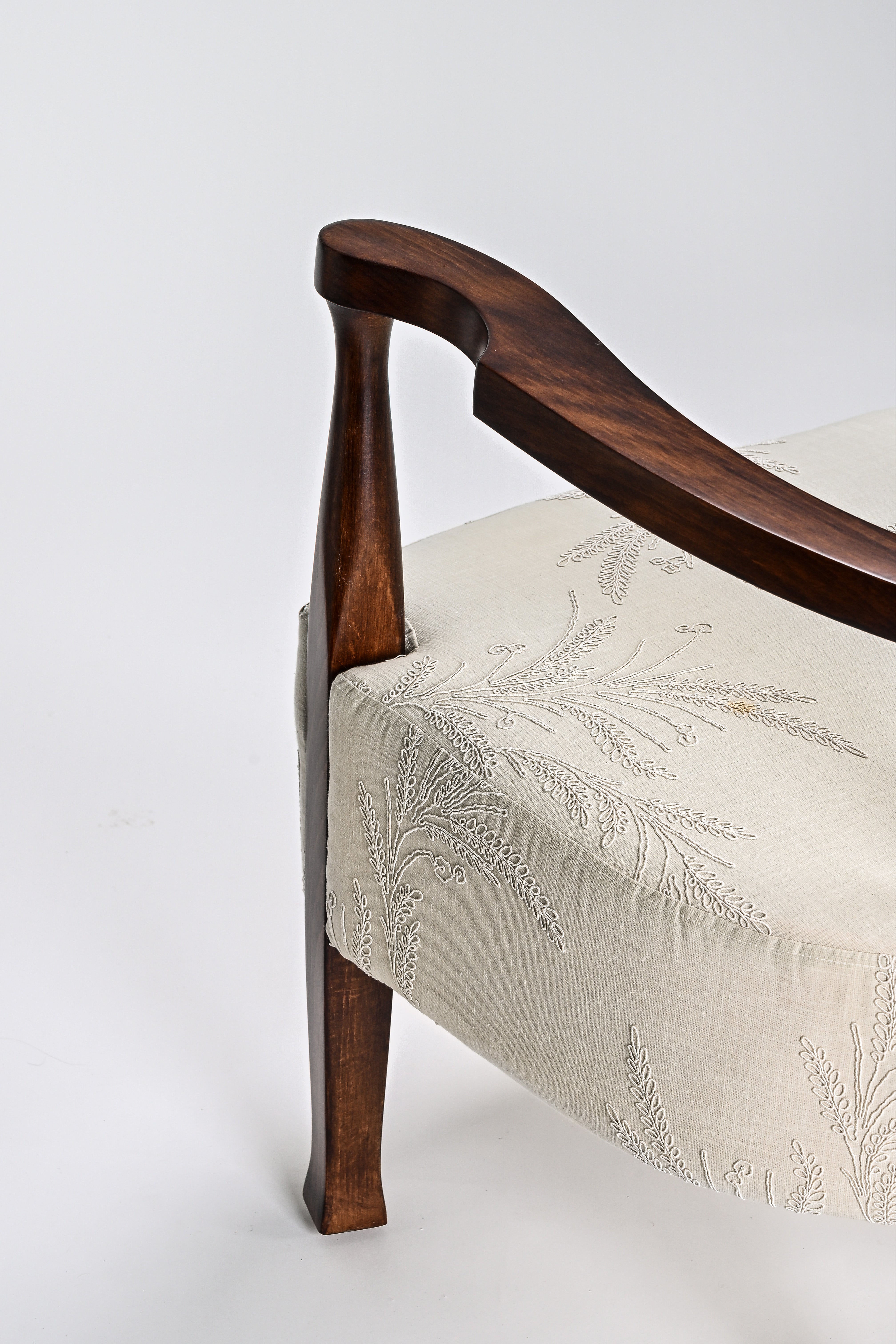 Chair with wooden armrests and floral embroidery on a white background