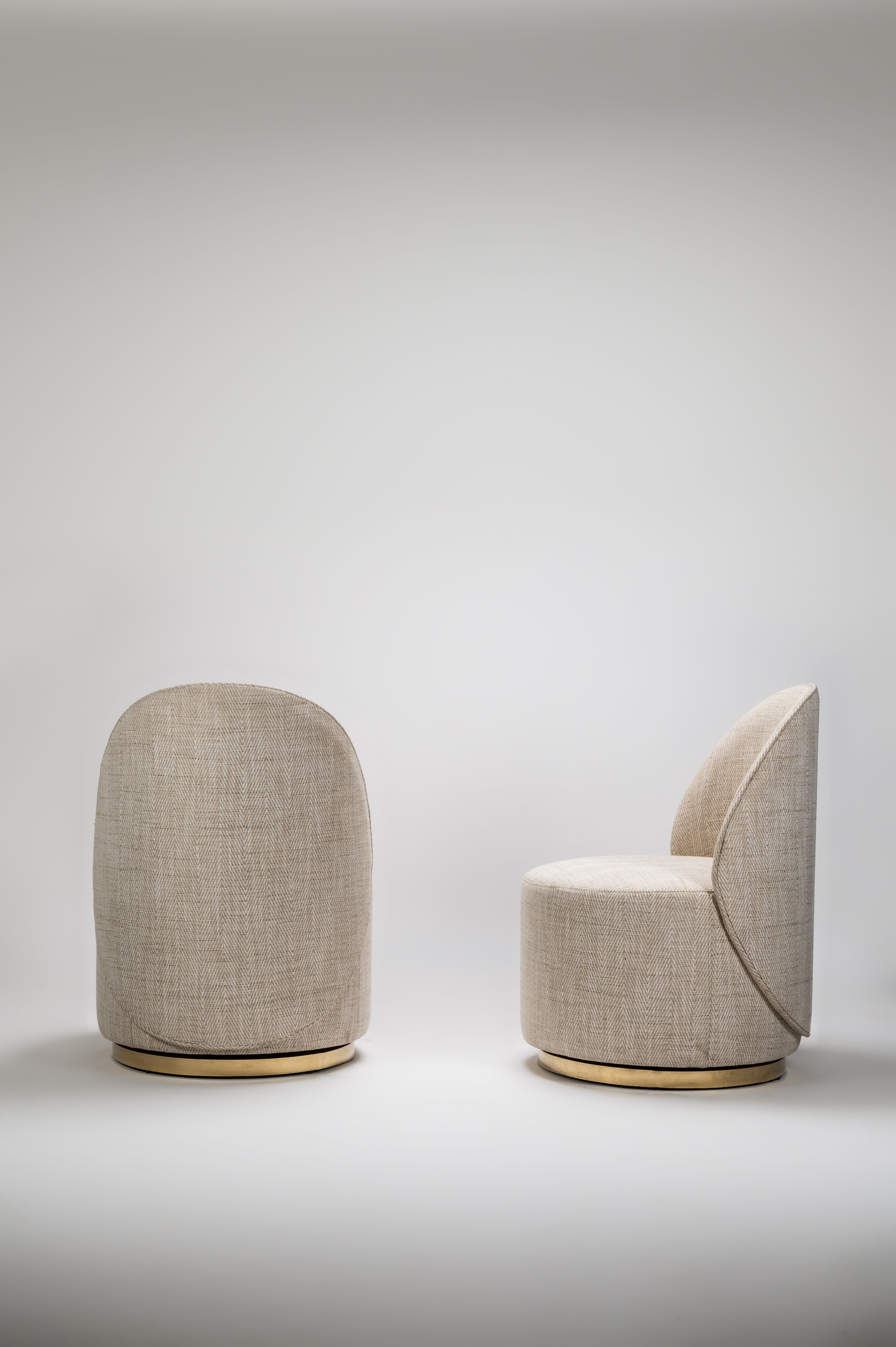Two beige chairs with a cylindrical ottoman on a light gray background