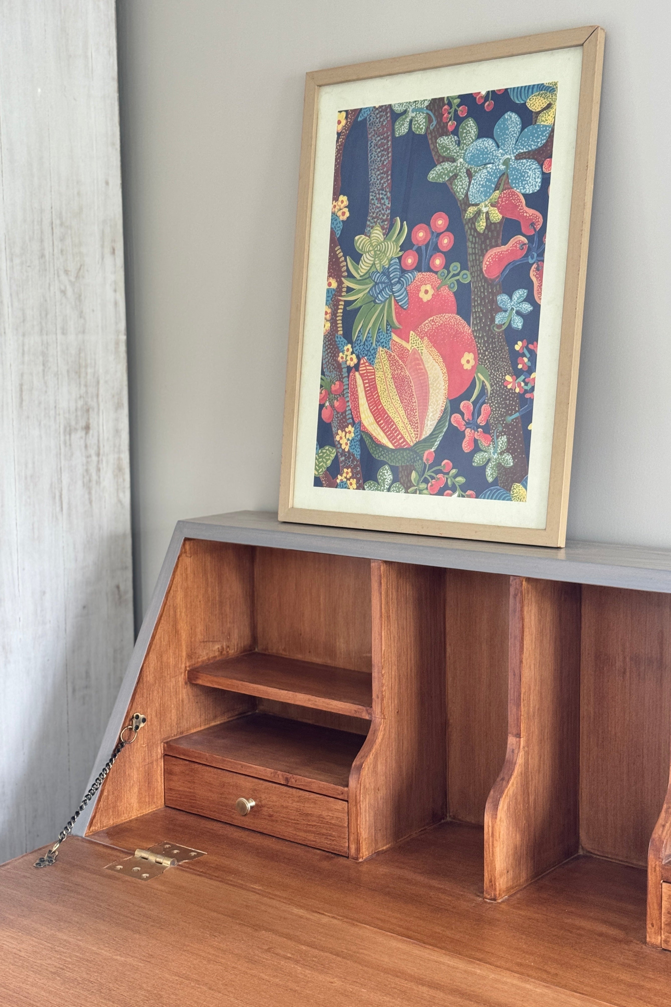 Wooden desk with a colorful framed picture on a gray wall