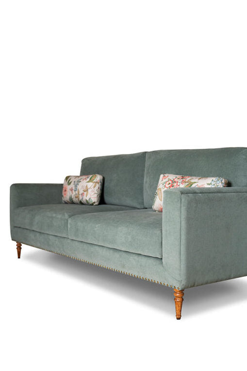 Green sofa with floral cushions on a white background