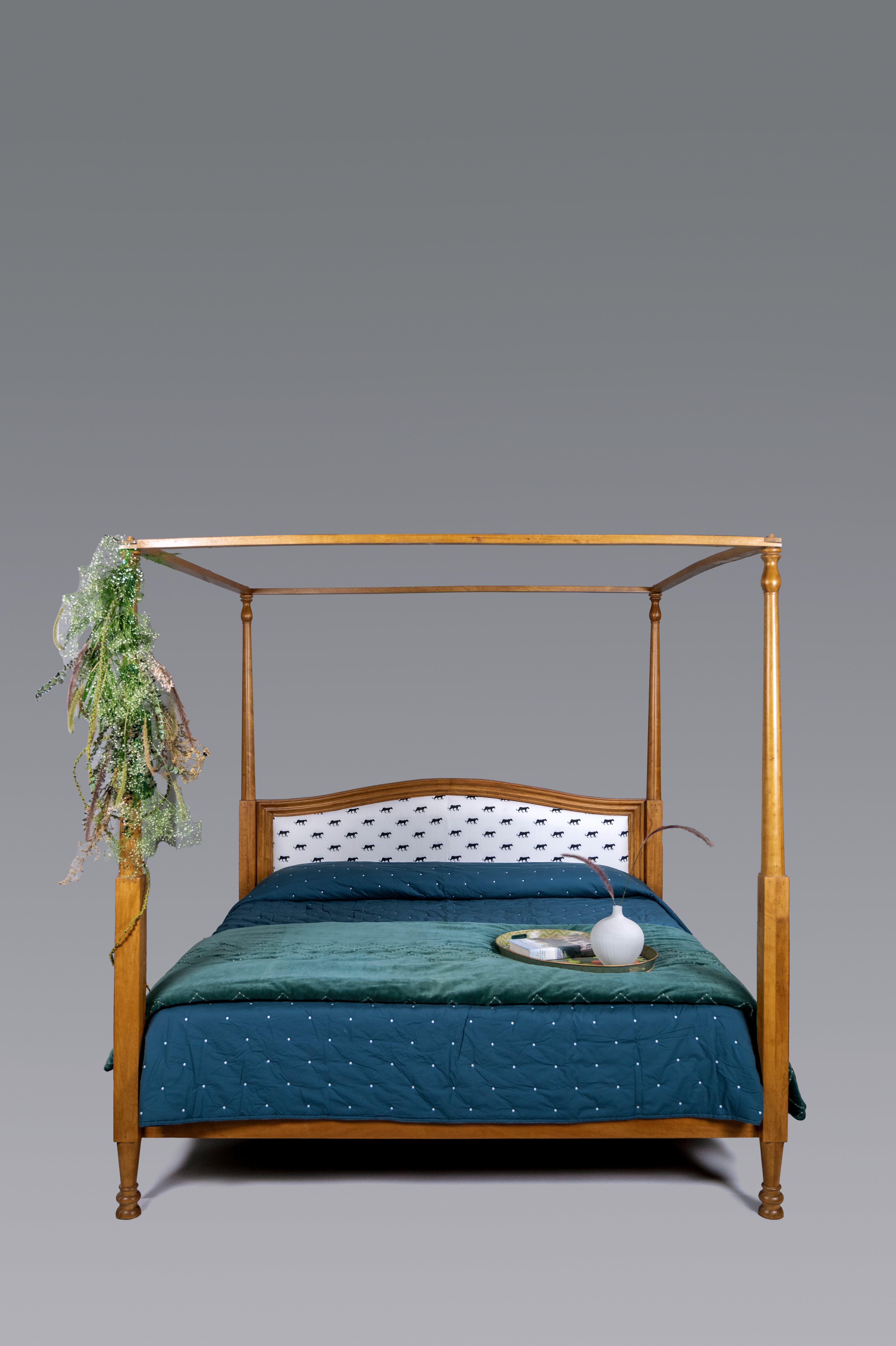 Four-poster bed with teal bedding and decorative elements on a gray background