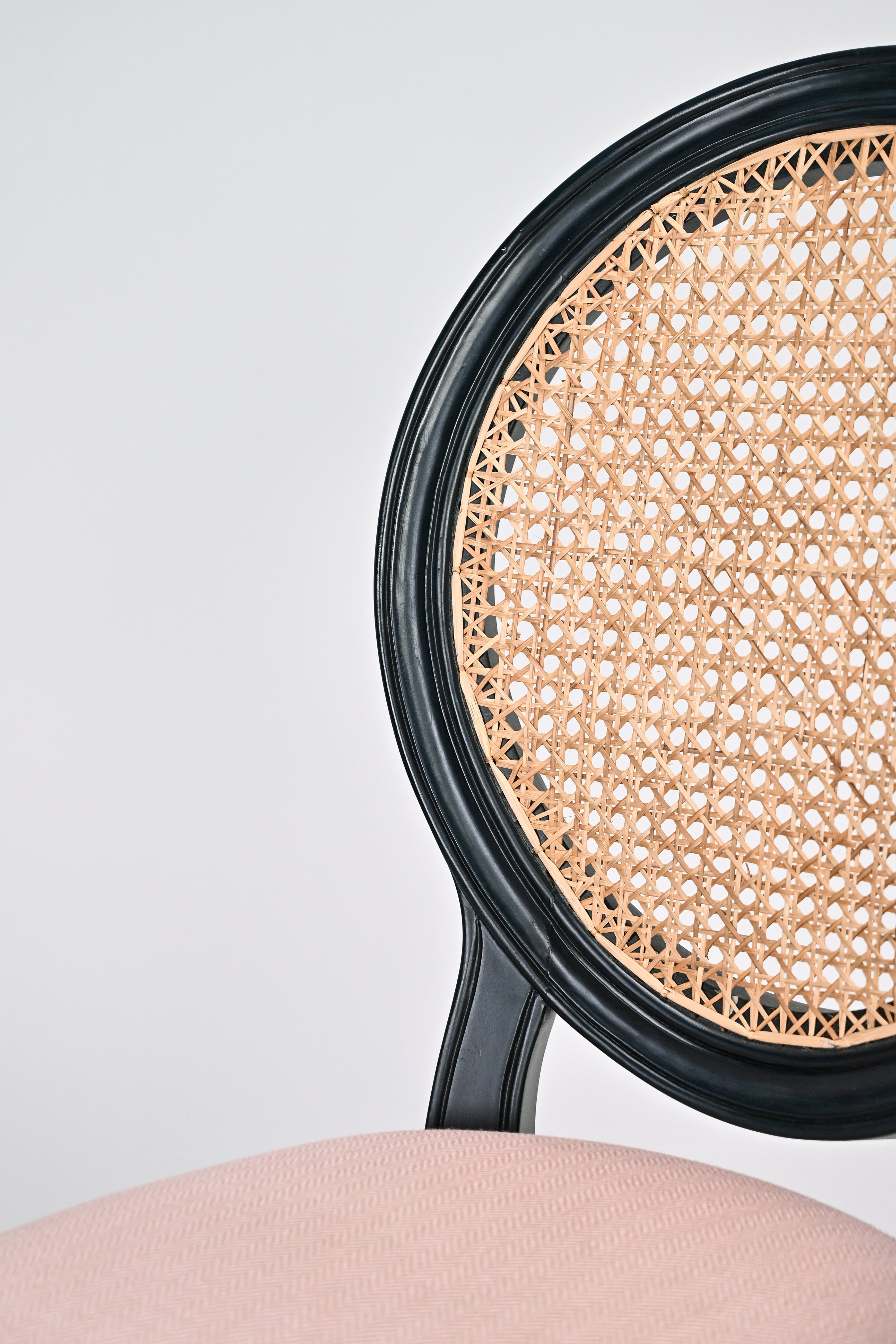 Close-up of a chair with wicker seat and black frame on a light gray background