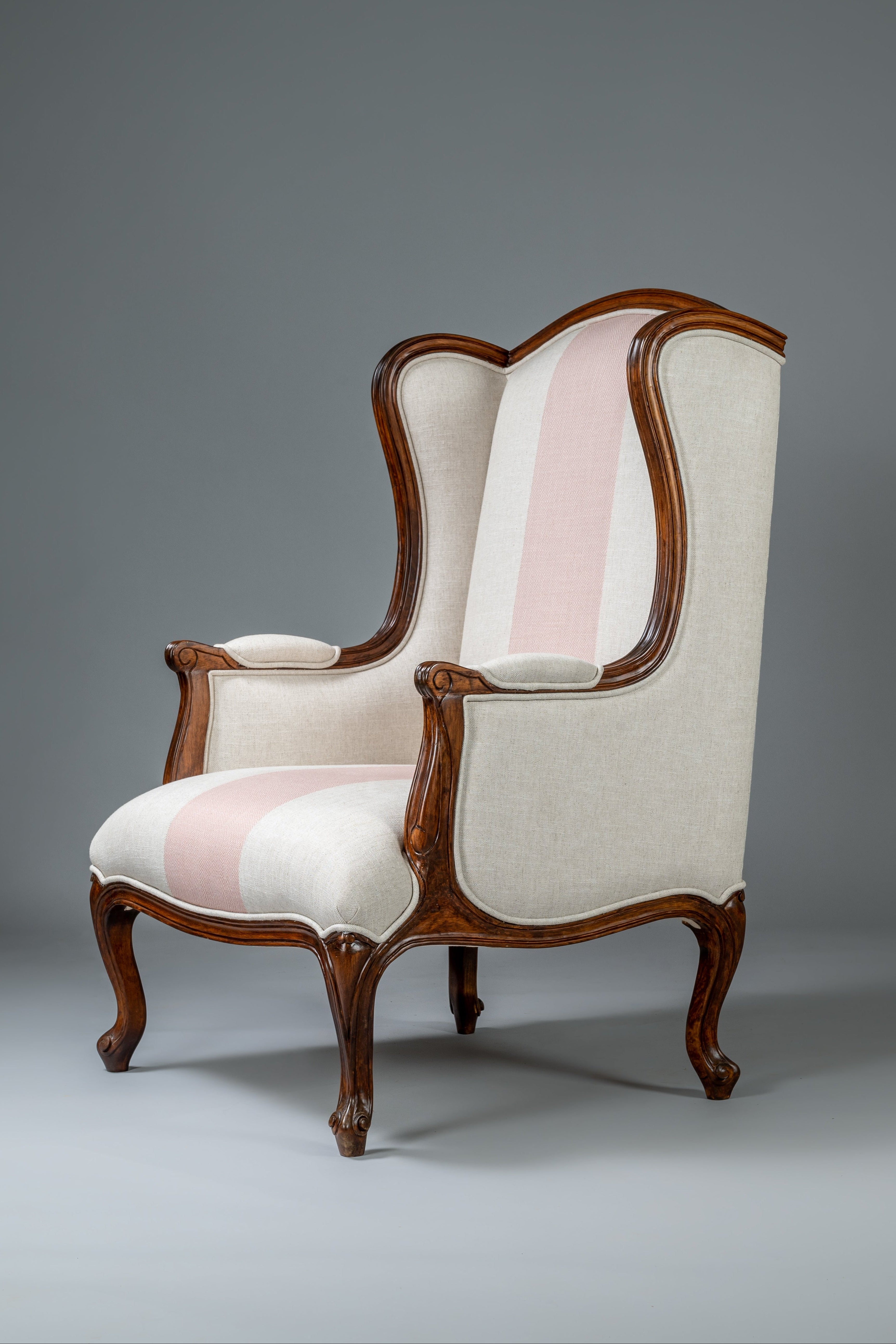 Decorative armchair with wooden frame and white and pink cushion on a gray background
