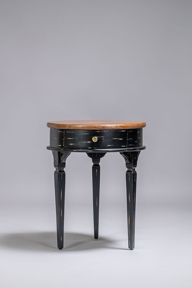 Round side table with black base and wooden top on a gray background