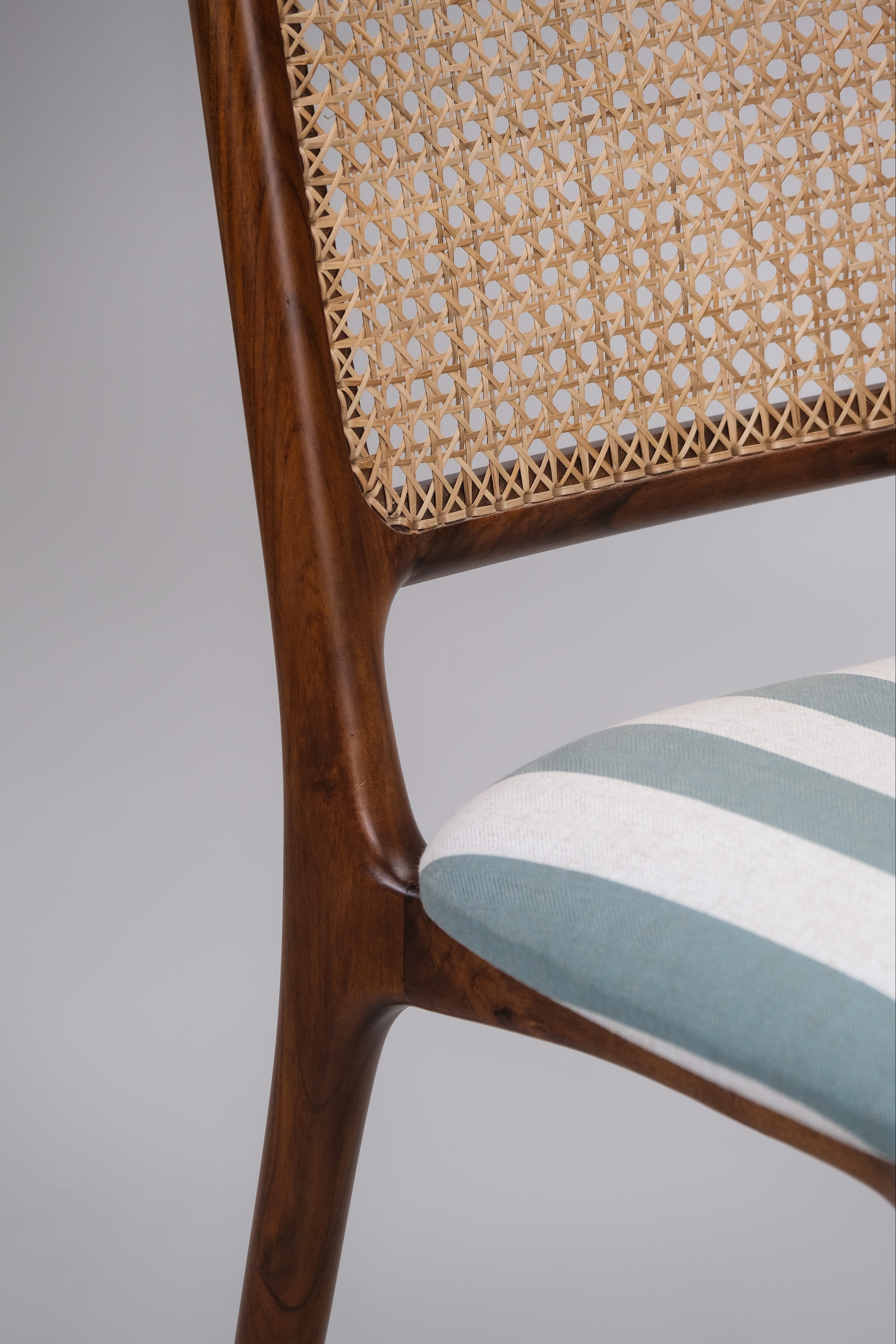 Chair with wicker backrest and striped cushion on a gray background