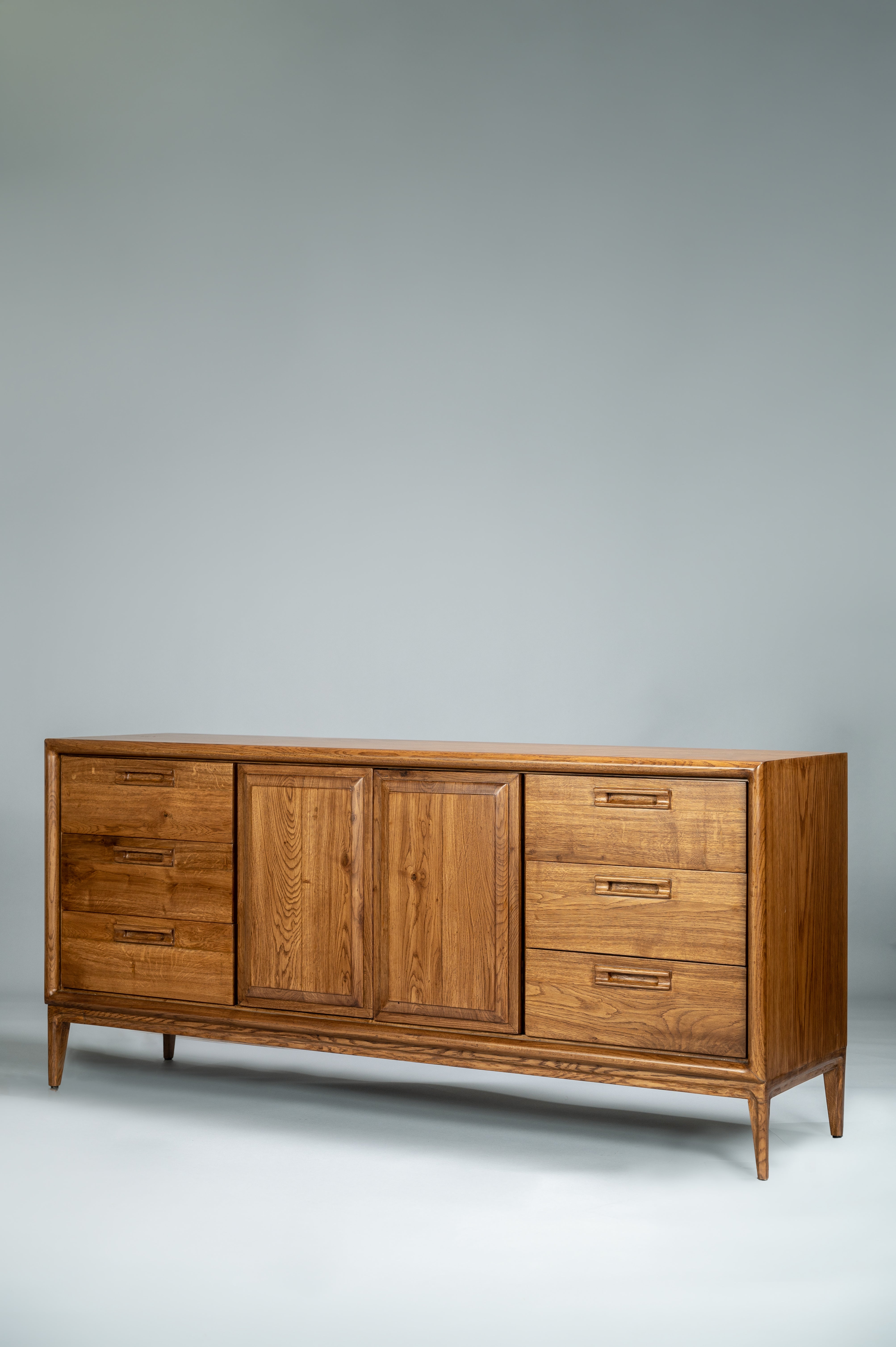 Wooden sideboard with multiple drawers and doors on a gray background
