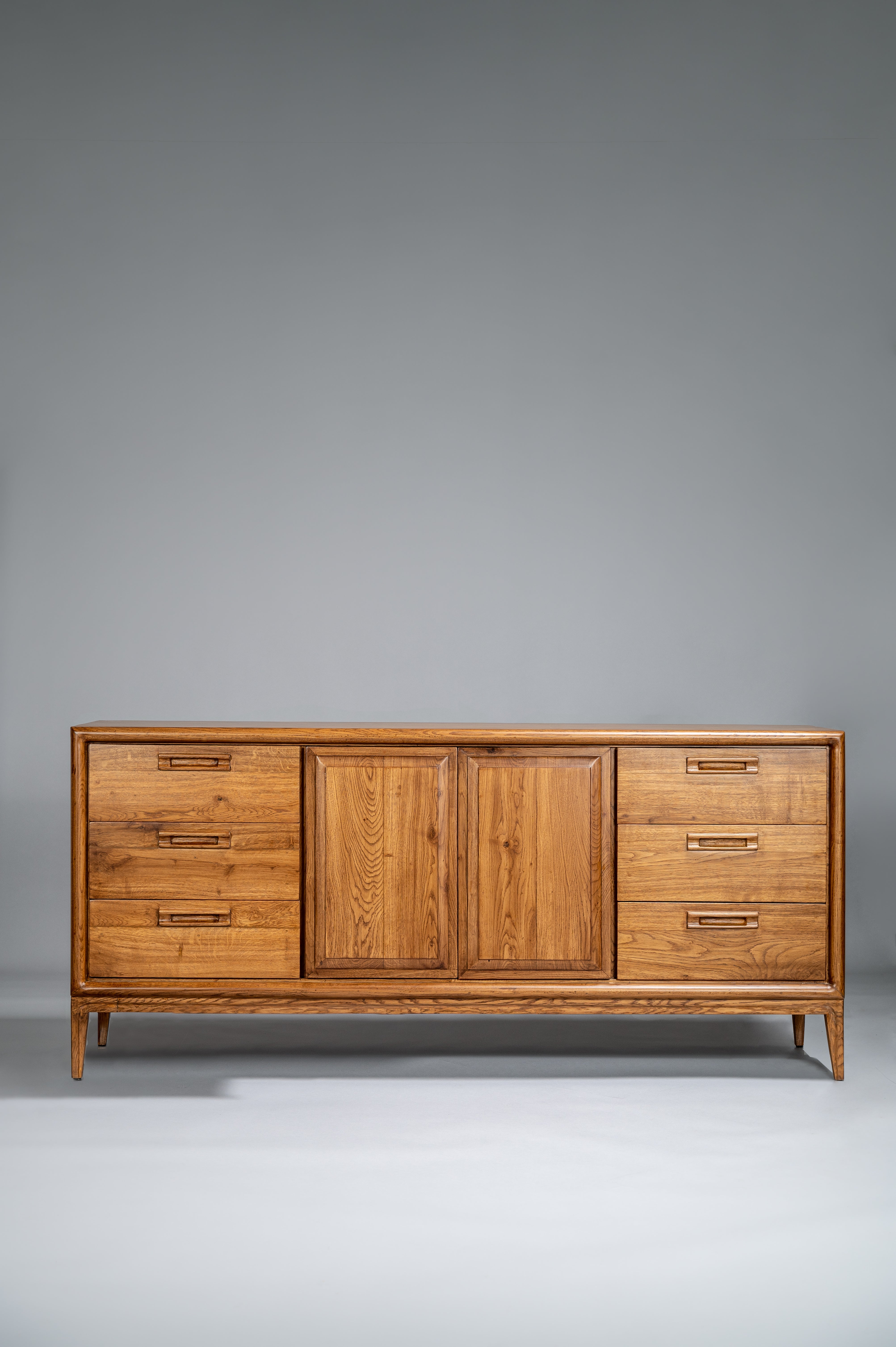 Wooden dresser with multiple drawers and doors on a gray background