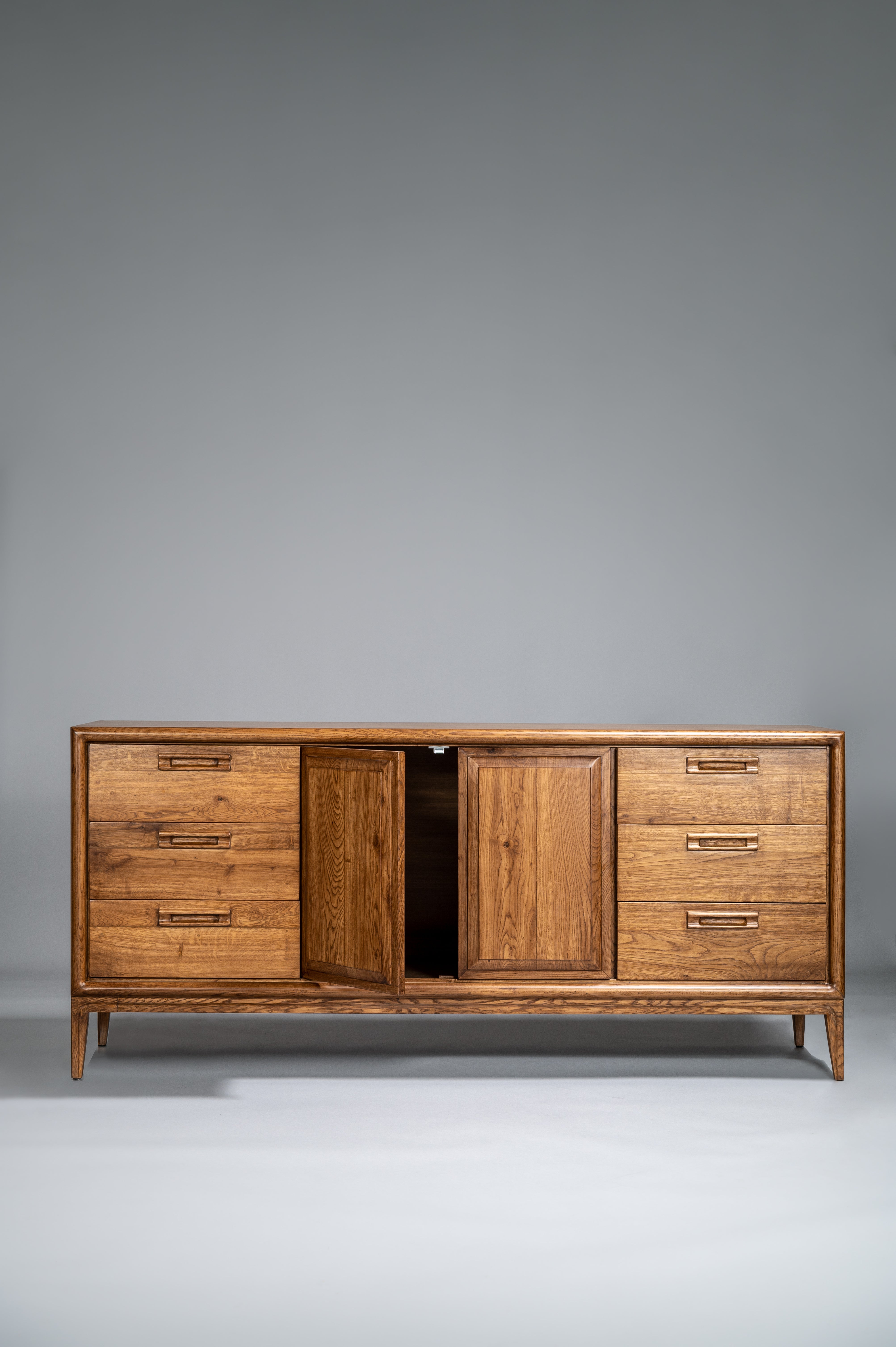 Wooden sideboard with multiple drawers and doors on a gray background