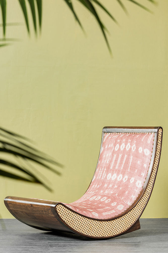 Modern lounge chair with pink cushion against a green wall