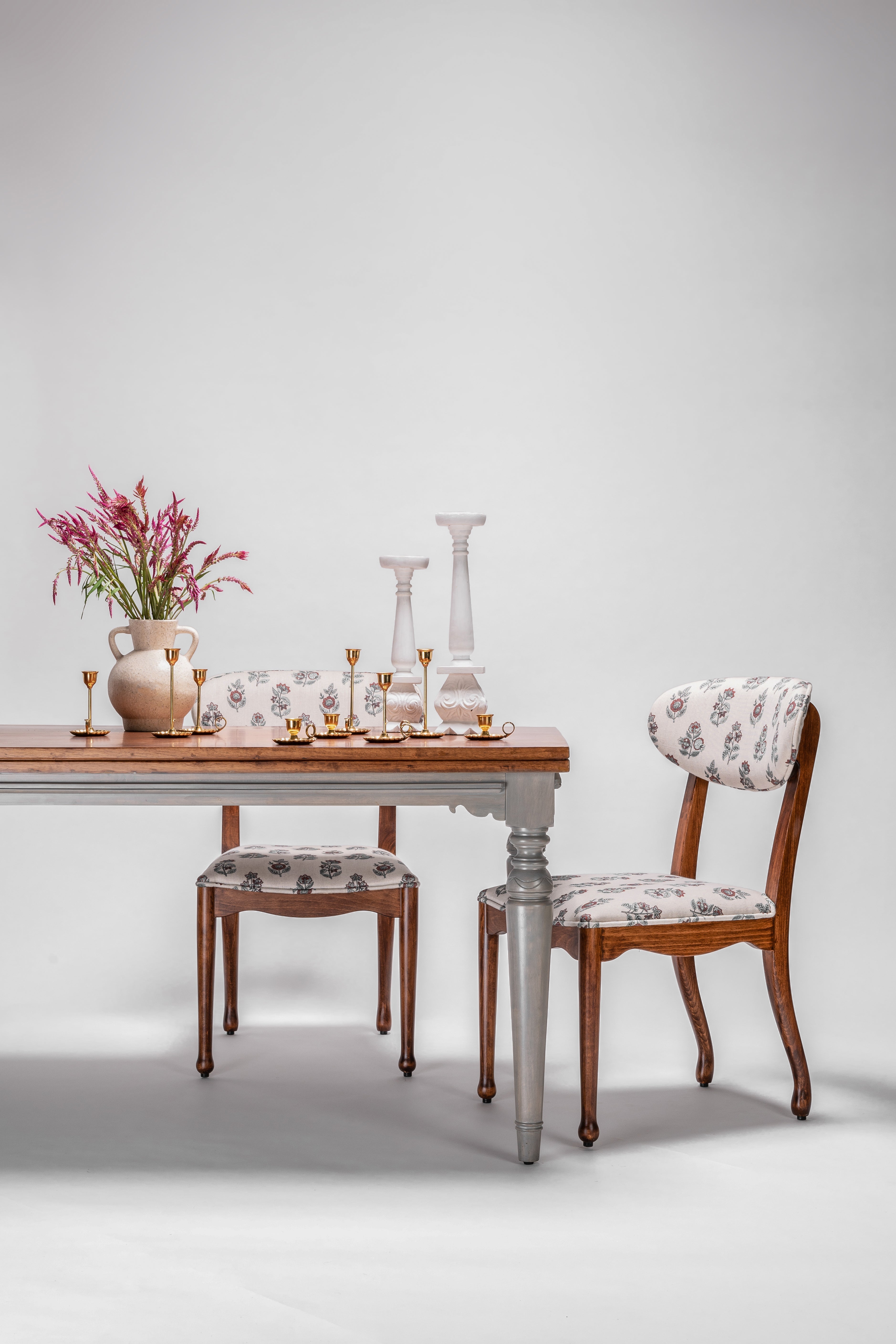 Dining table with chairs and decorative items on a plain background