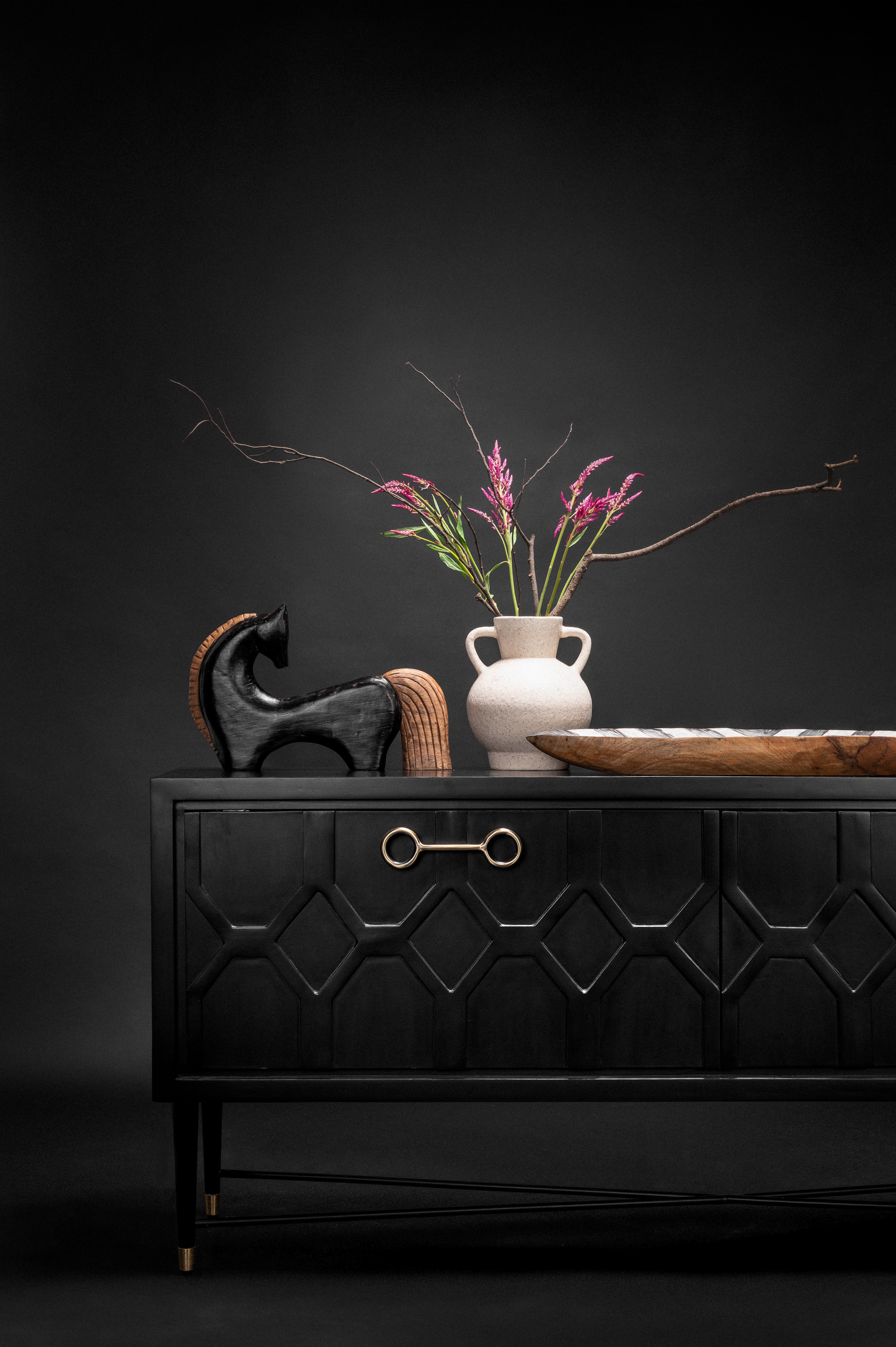 Black dresser with decorative items against a dark background