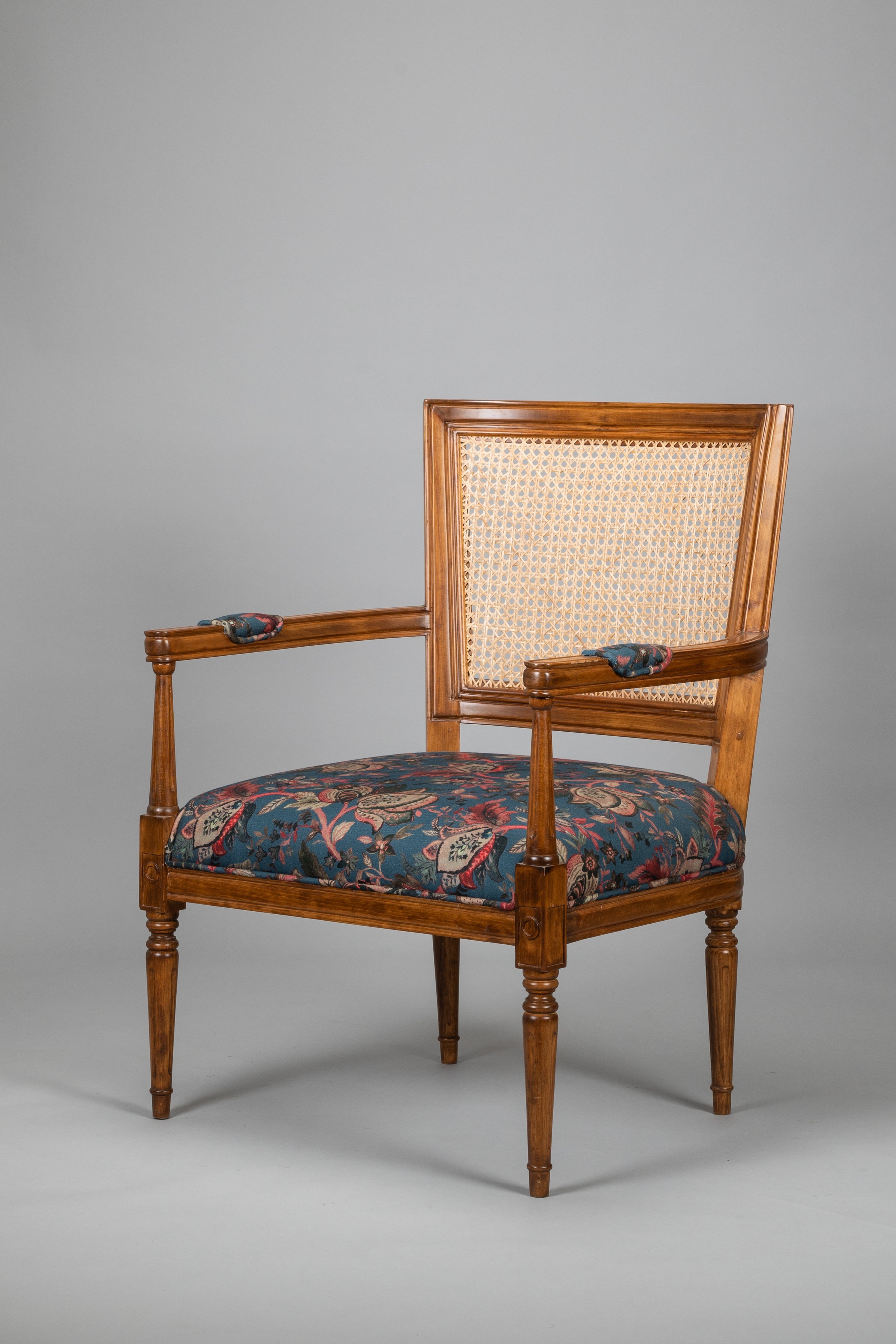 Wooden armchair with floral cushion on a gray background