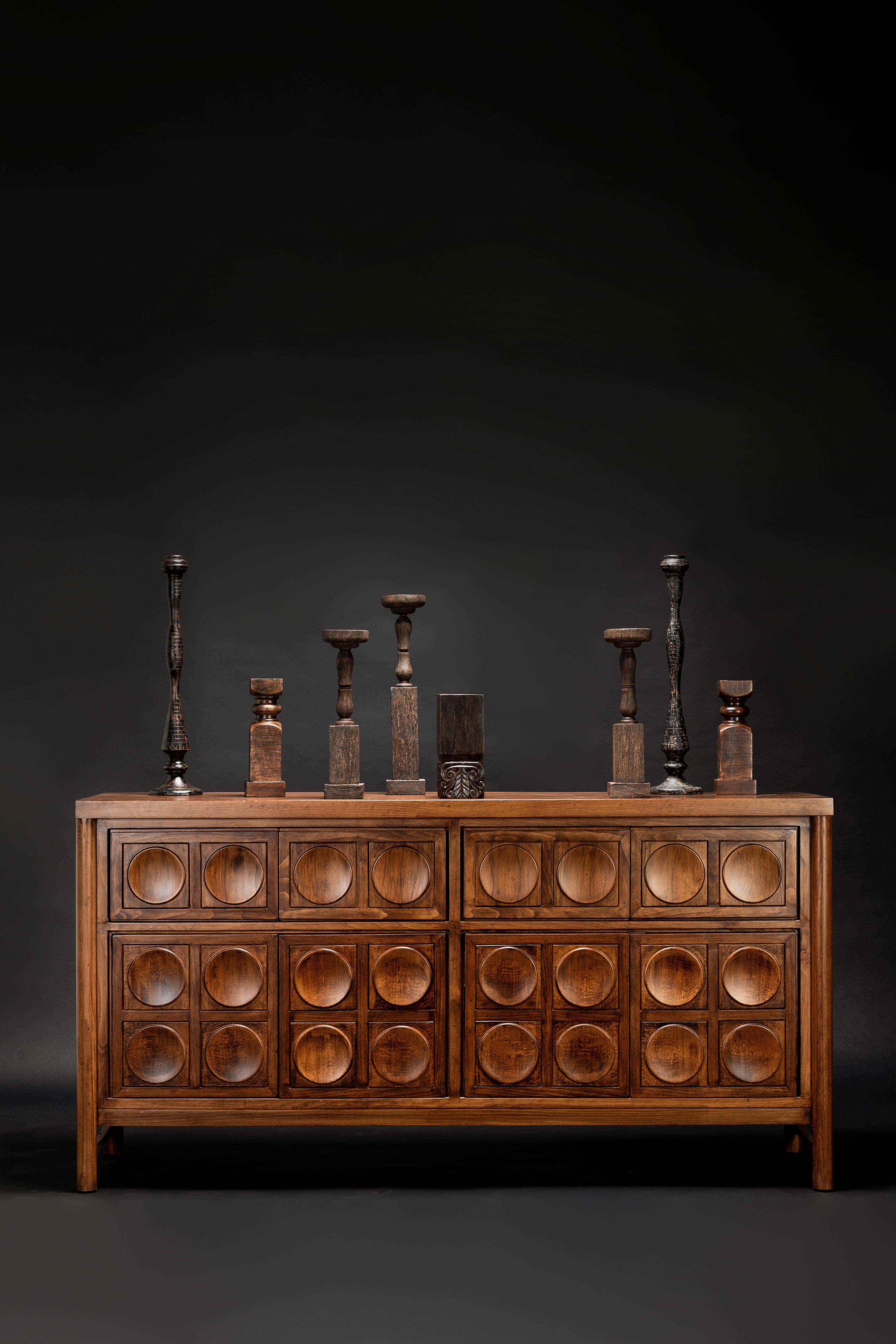 Wooden dresser with circular patterns and decorative items on a dark background
