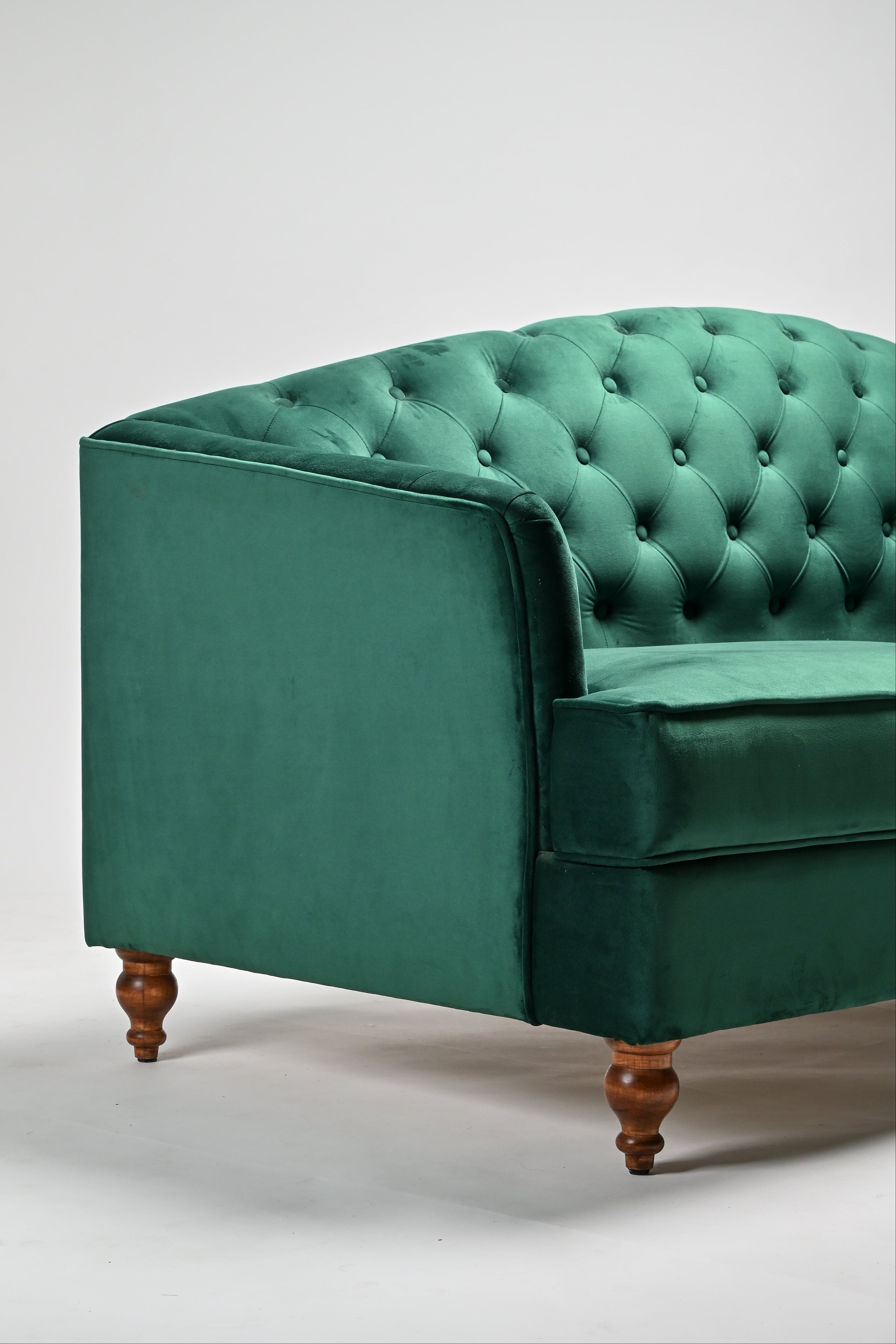 Green velvet sofa with wooden legs on a white background