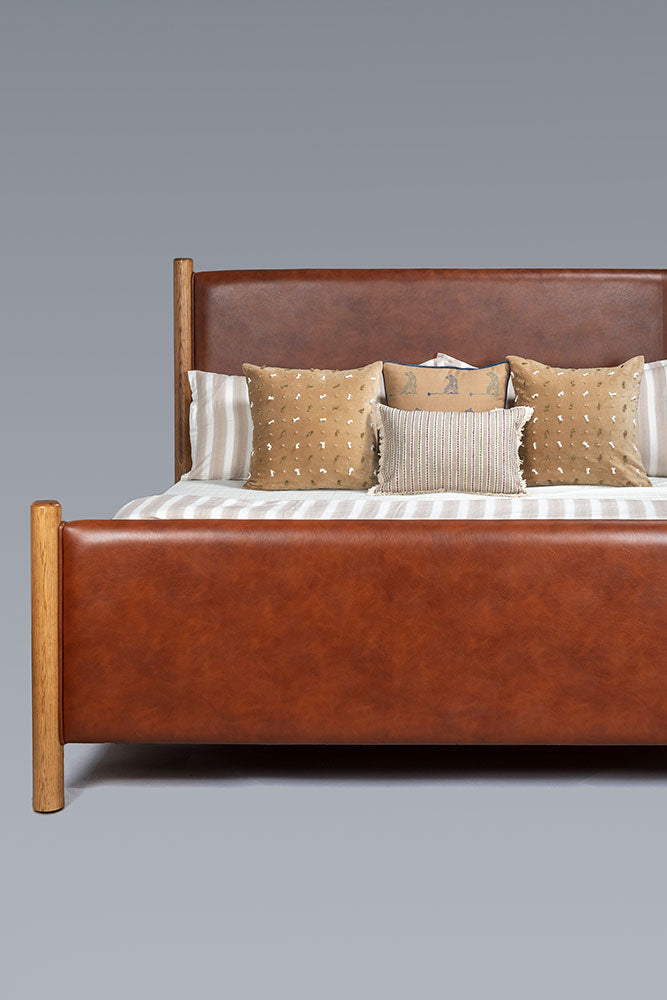 Brown leather bed with pillows on a gray background