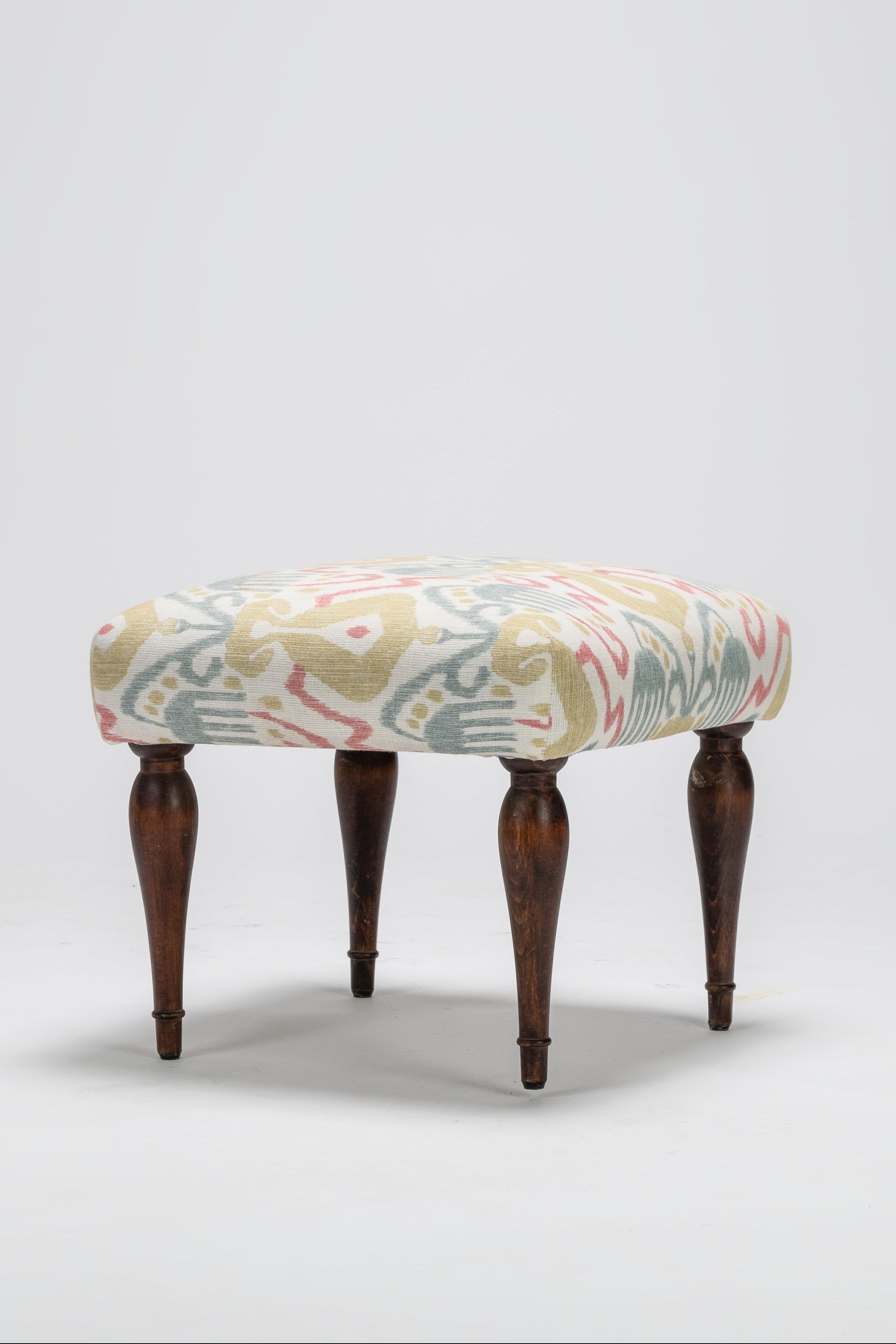 Decorative stool with patterned top and wooden legs on a white background