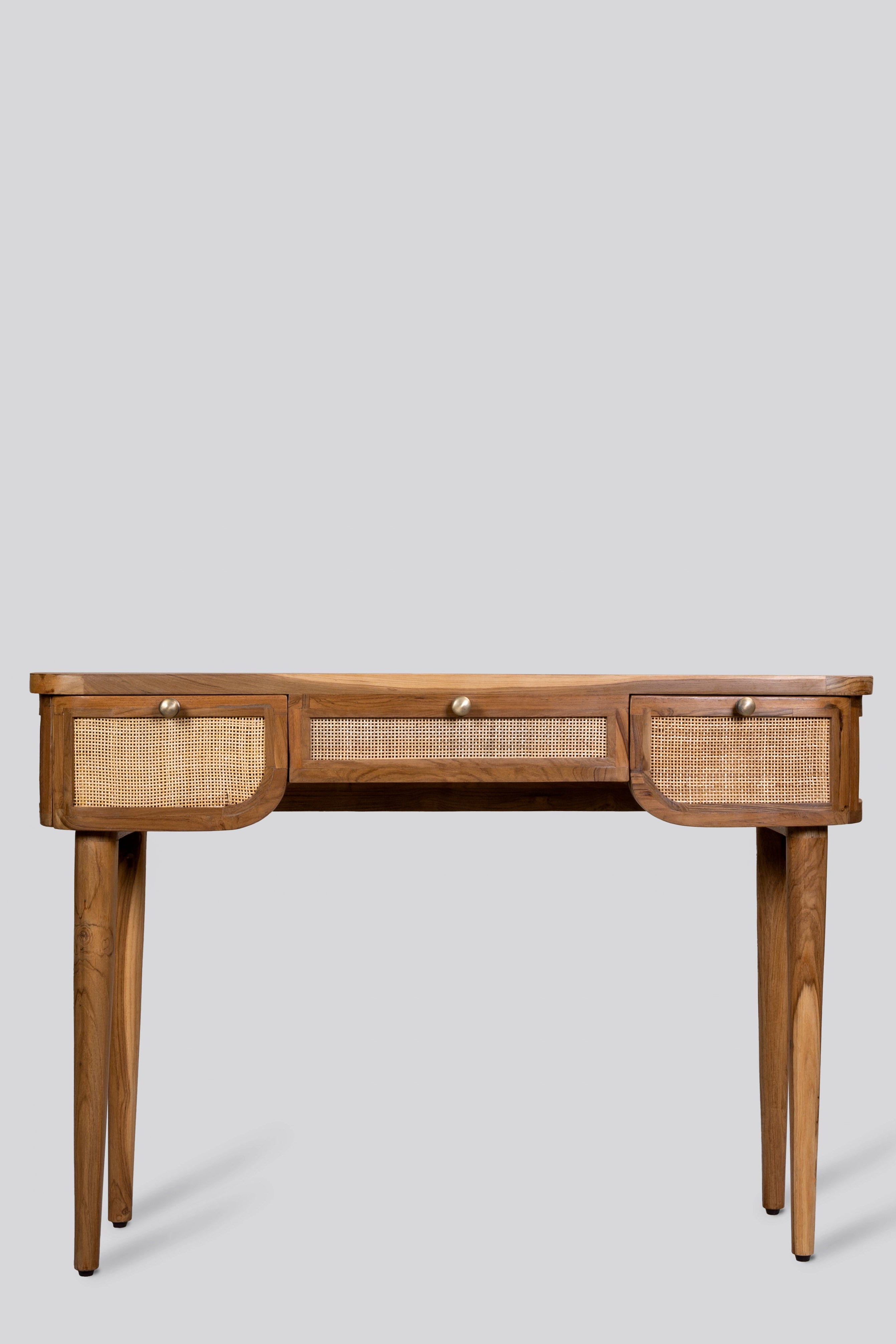 Wooden desk with wicker drawers on a light gray background