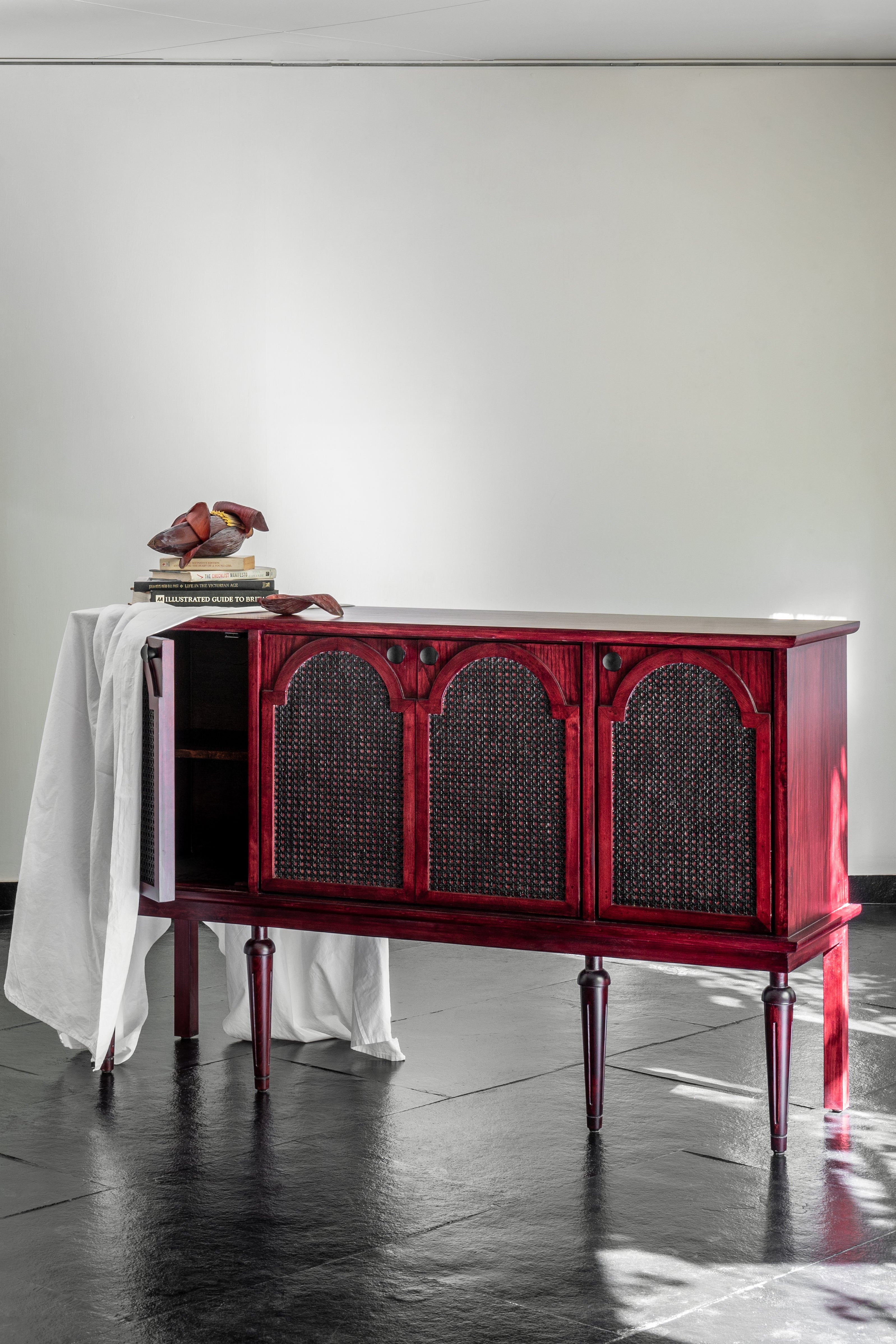 Red sideboard in a minimalistic room with white walls and dark floor.