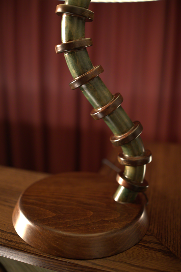Decorative lamp with wooden base and green, ribbed neck on a wooden surface.