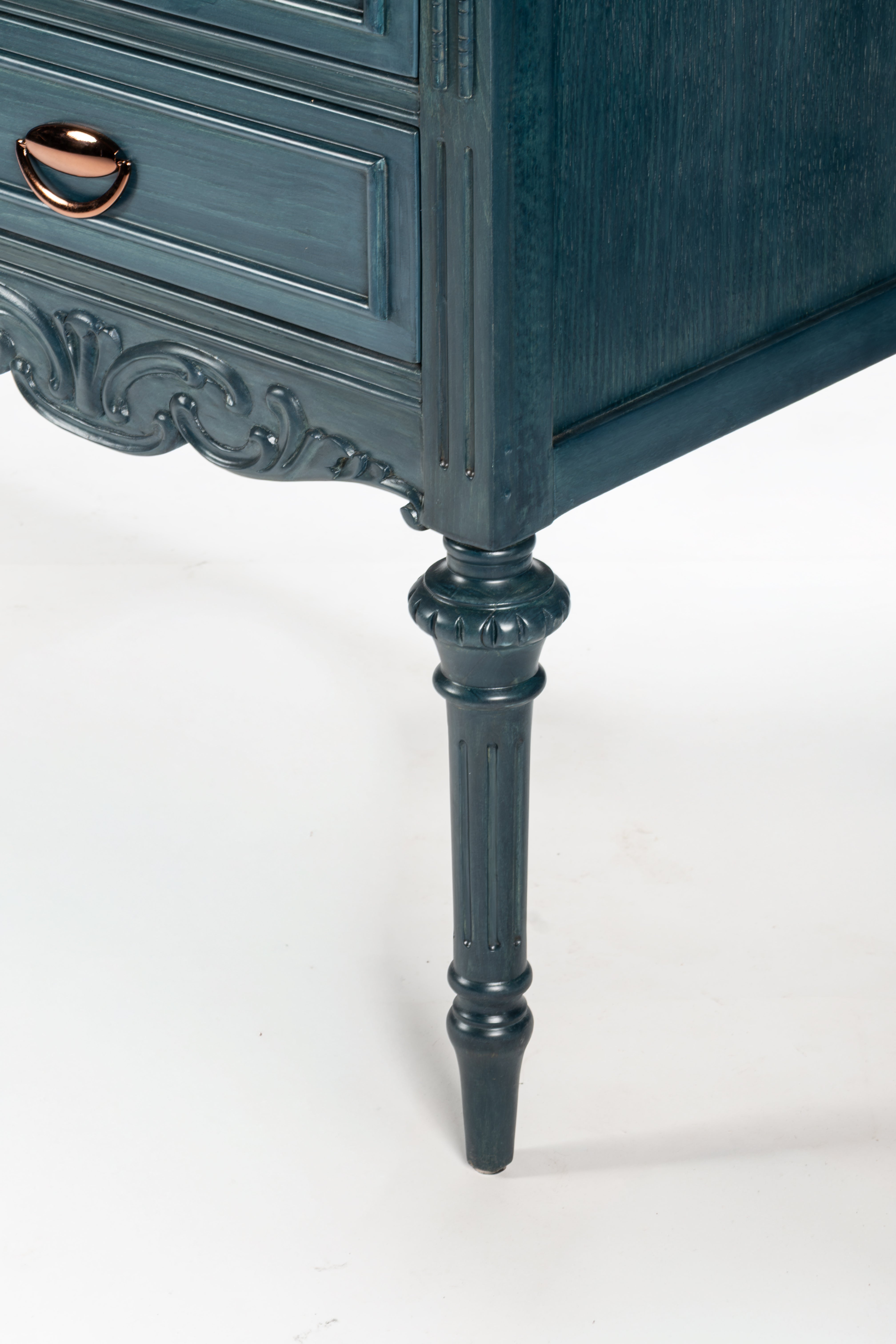 Close-up of a dark blue ornate dresser leg on a white background