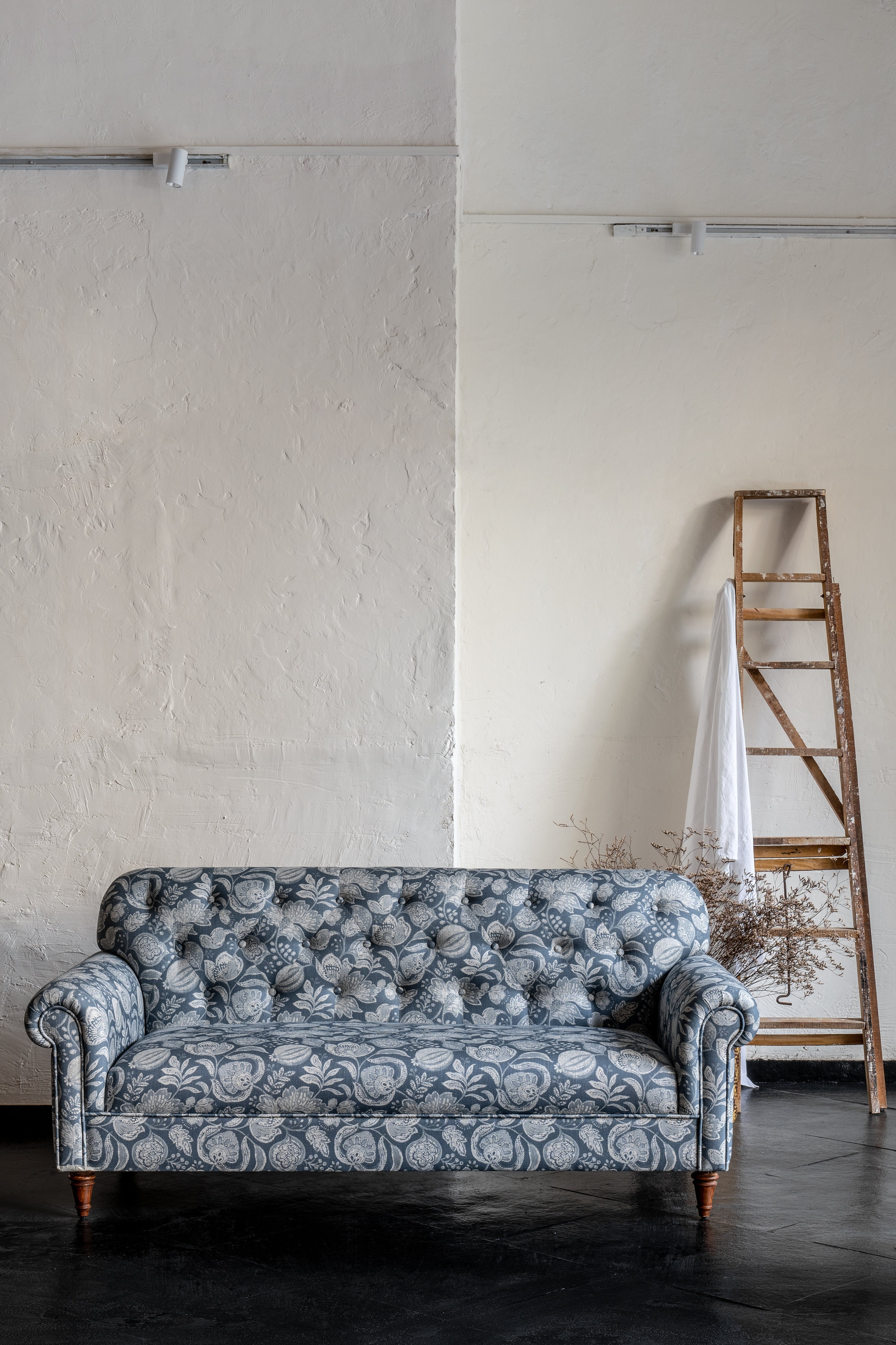 Patterned sofa in a minimalistic room with a ladder against the wall.