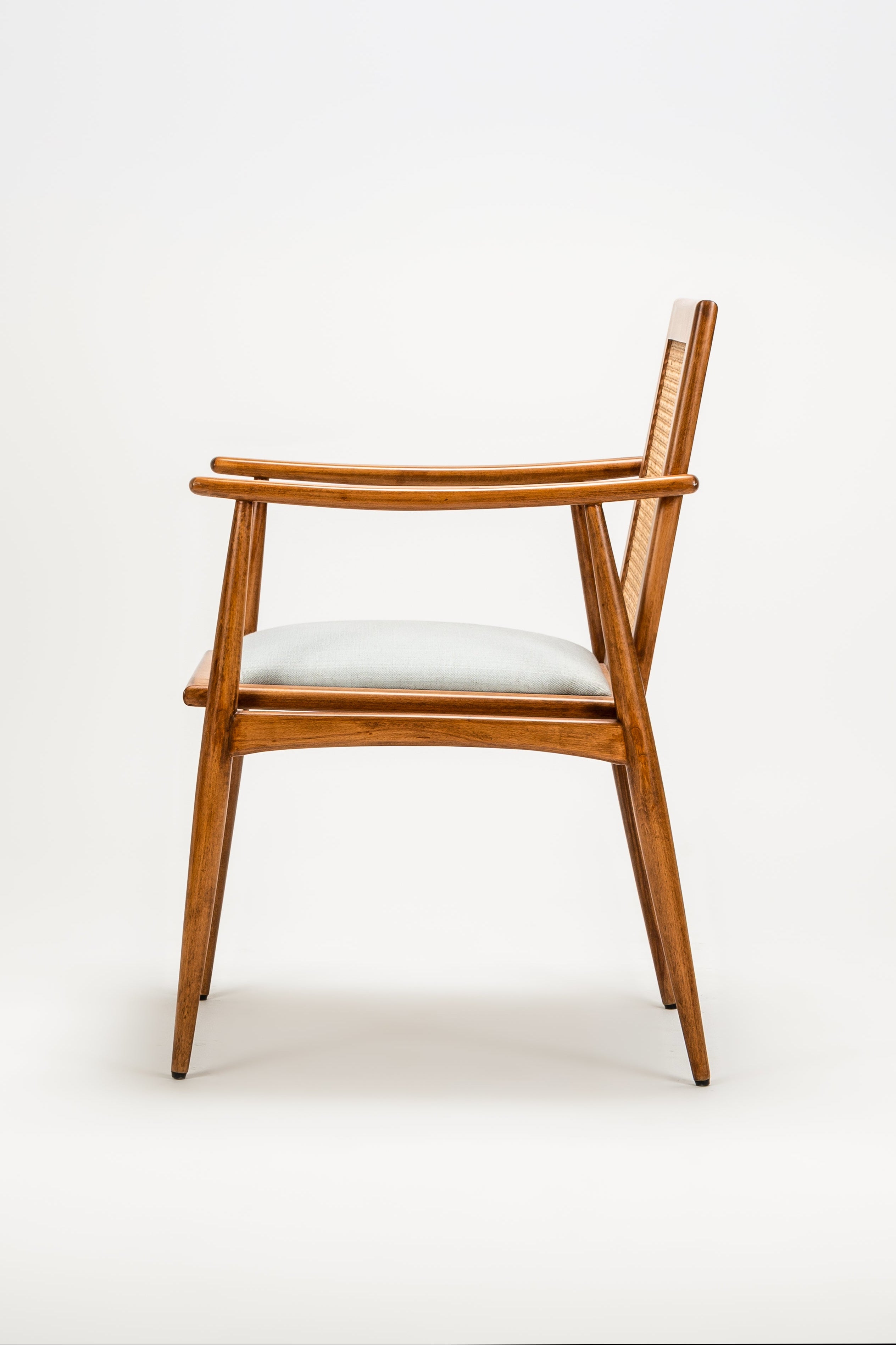 Wooden chair with a white cushion on a light gray background