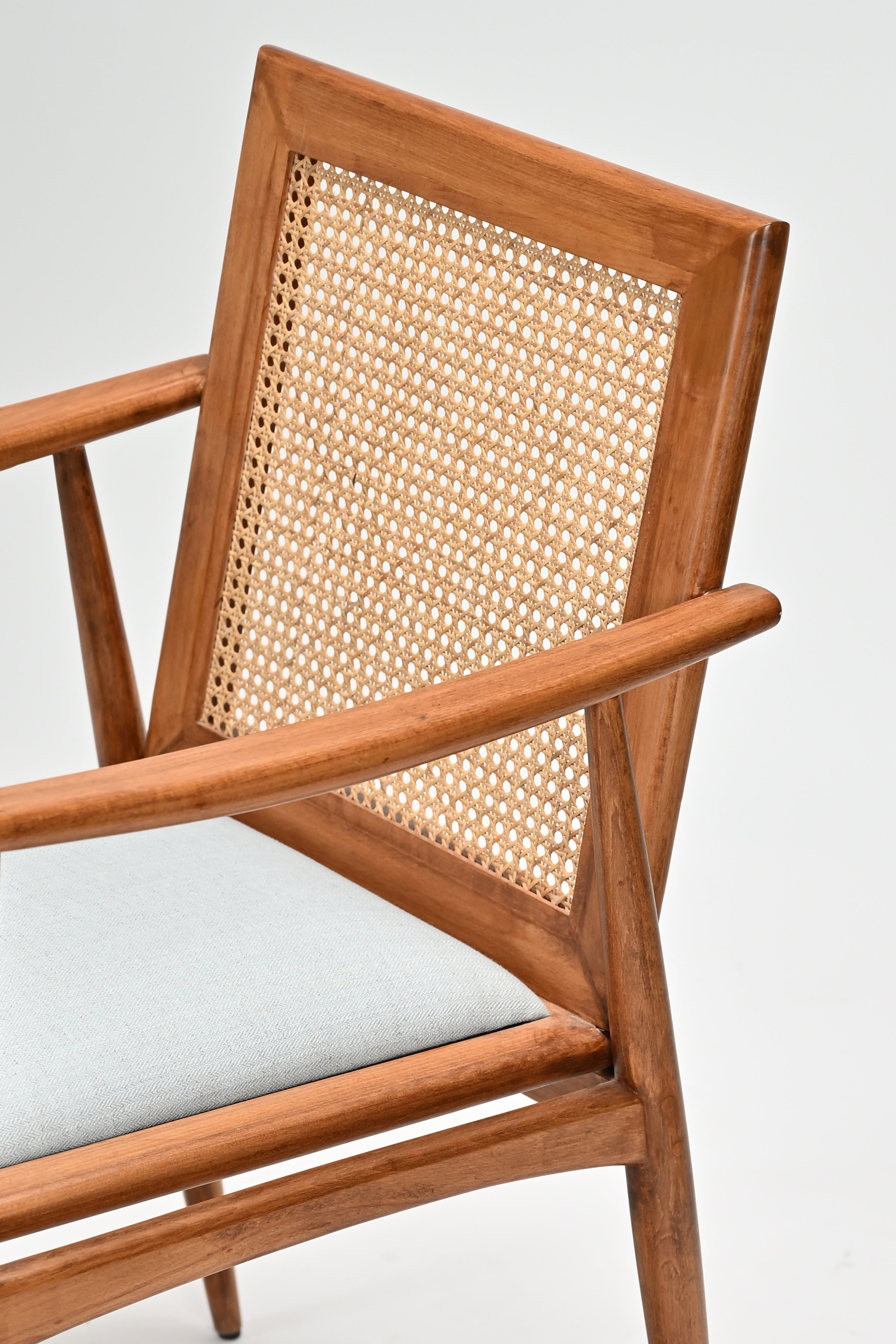 Wooden chair with wicker backrest and white cushion on a light gray background