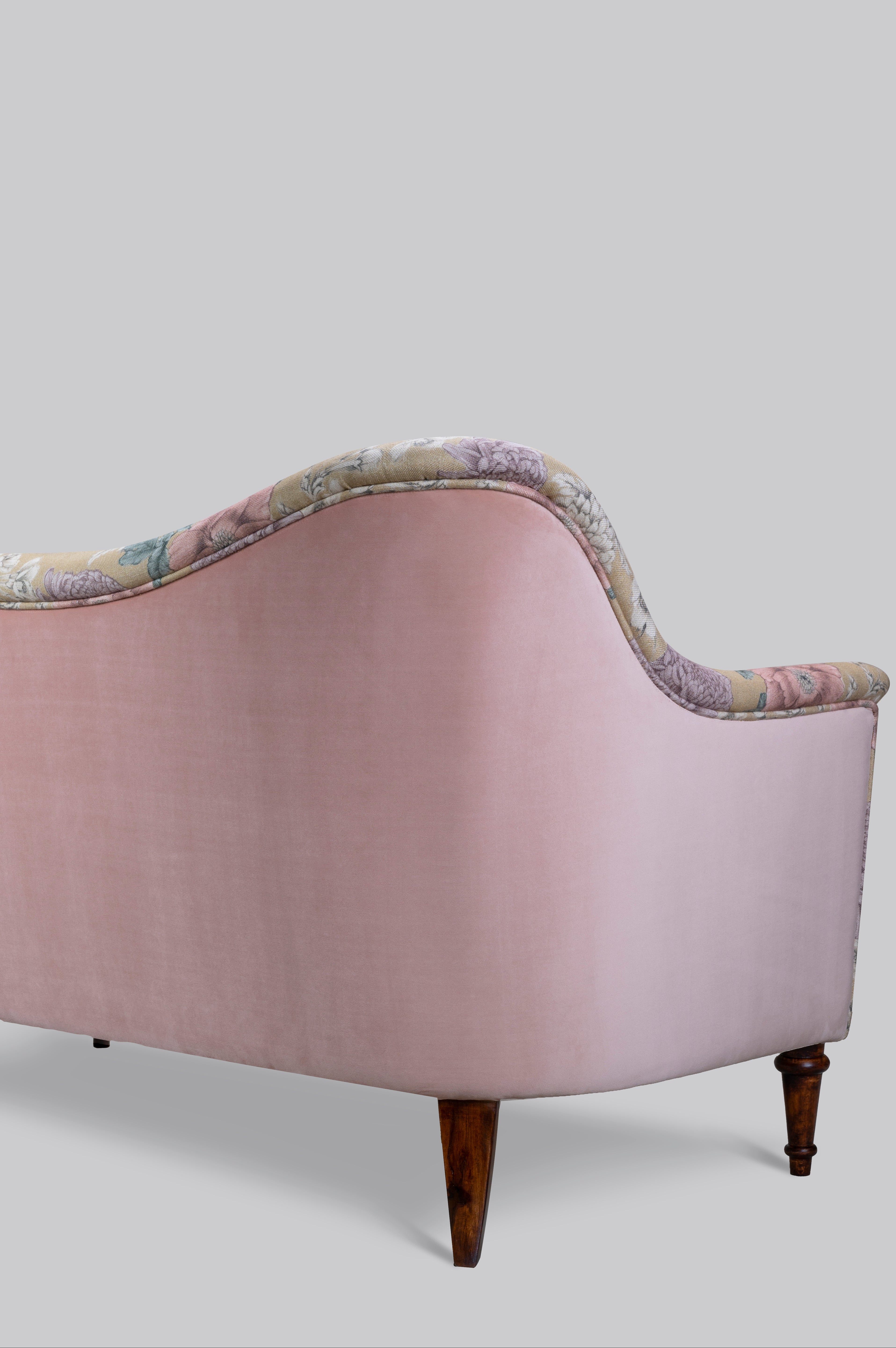 Pink sofa with floral-patterned backrest on a light gray background