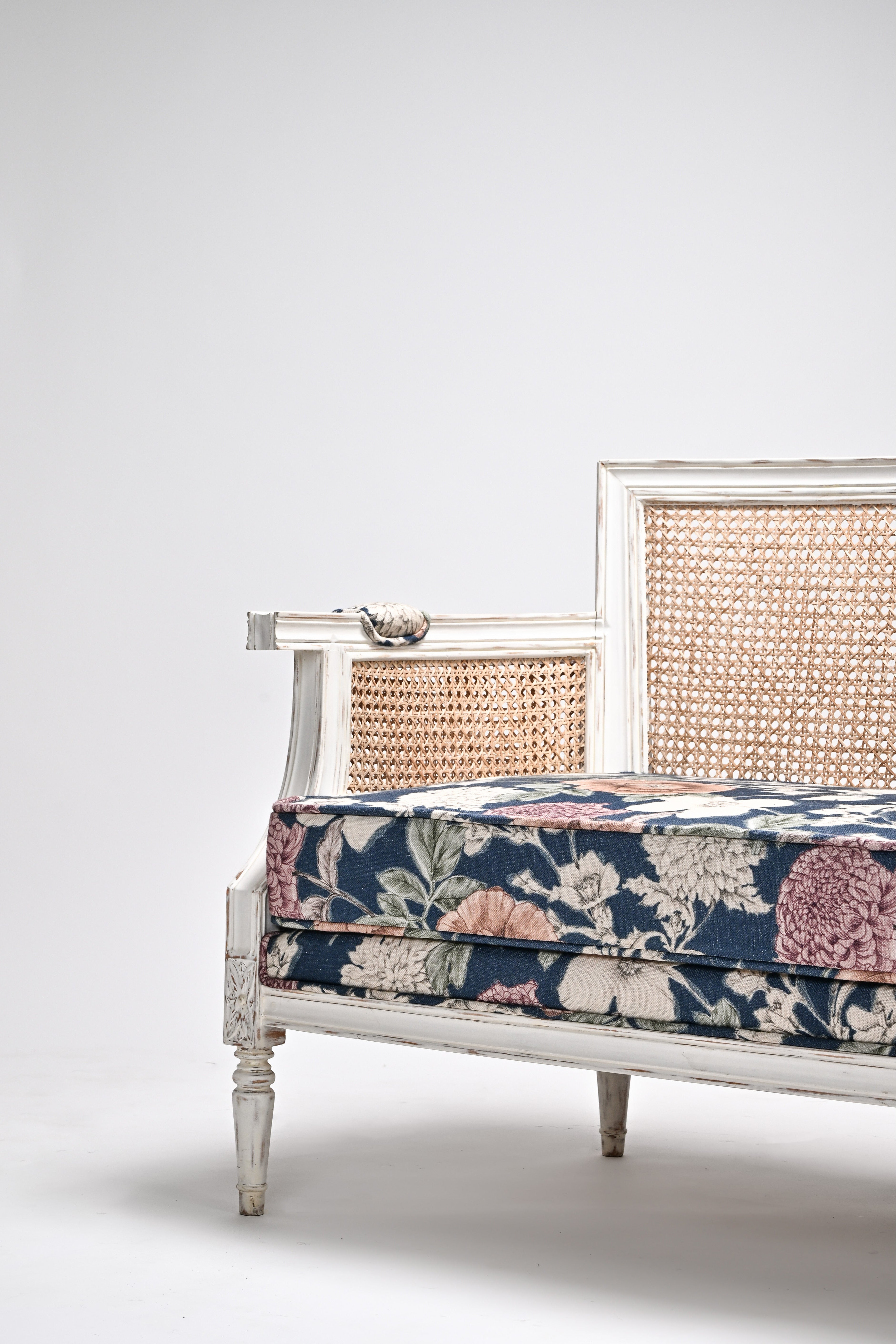Vintage-style bench with floral pattern and wicker backrest on a white background