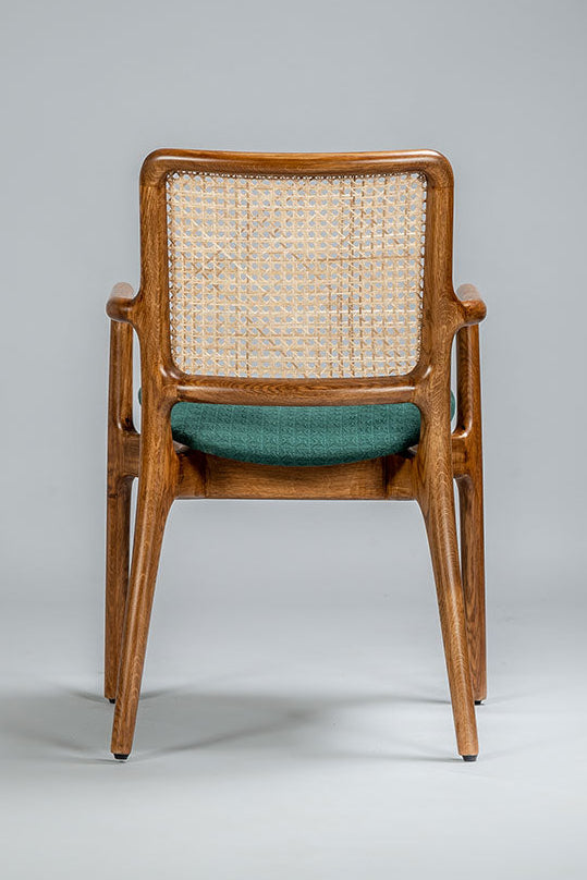 Wooden chair with wicker backrest and green cushion on a gray background