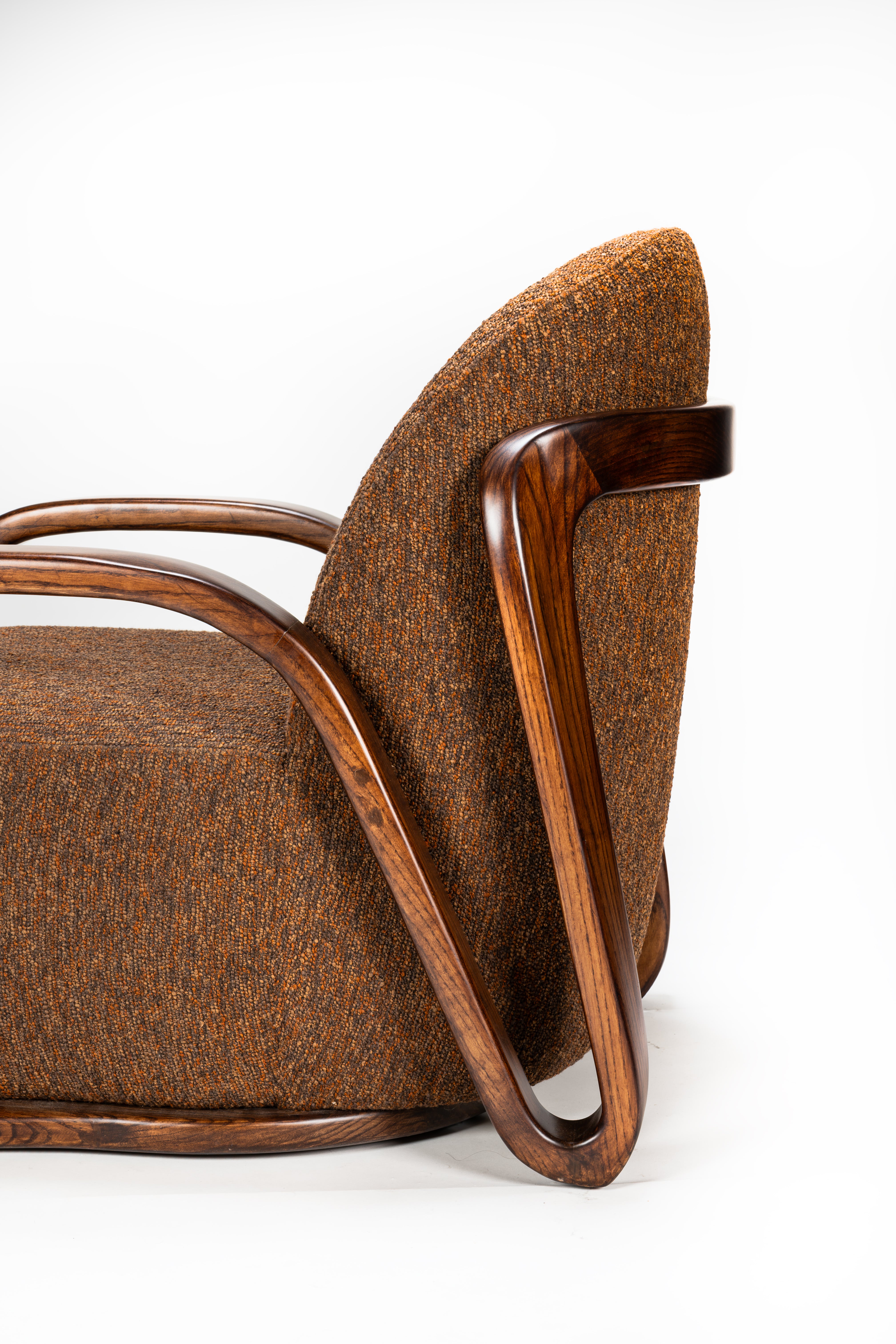 Brown upholstered chair with wooden armrests on a white background