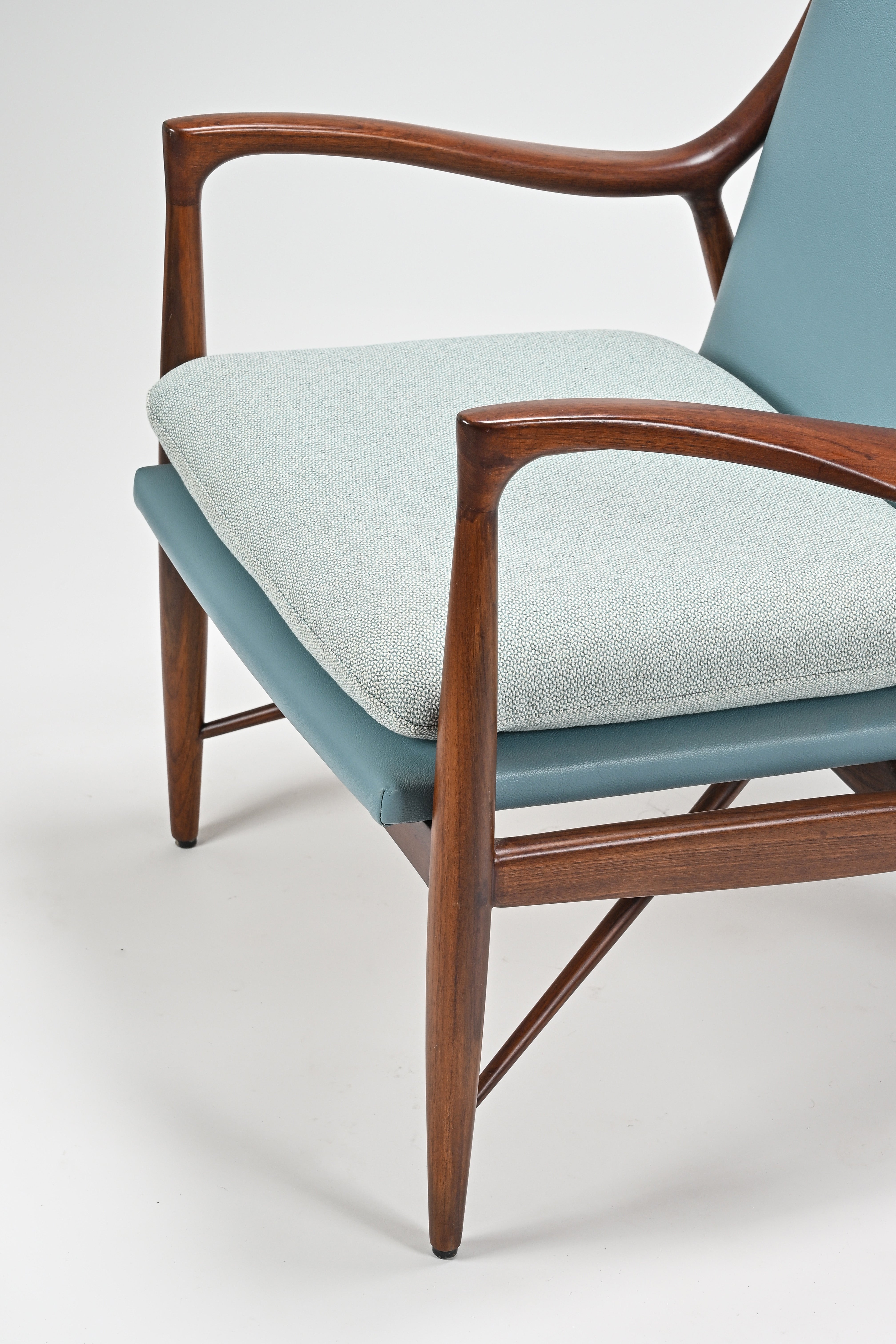 Chair with wooden frame and light blue cushion on a white background