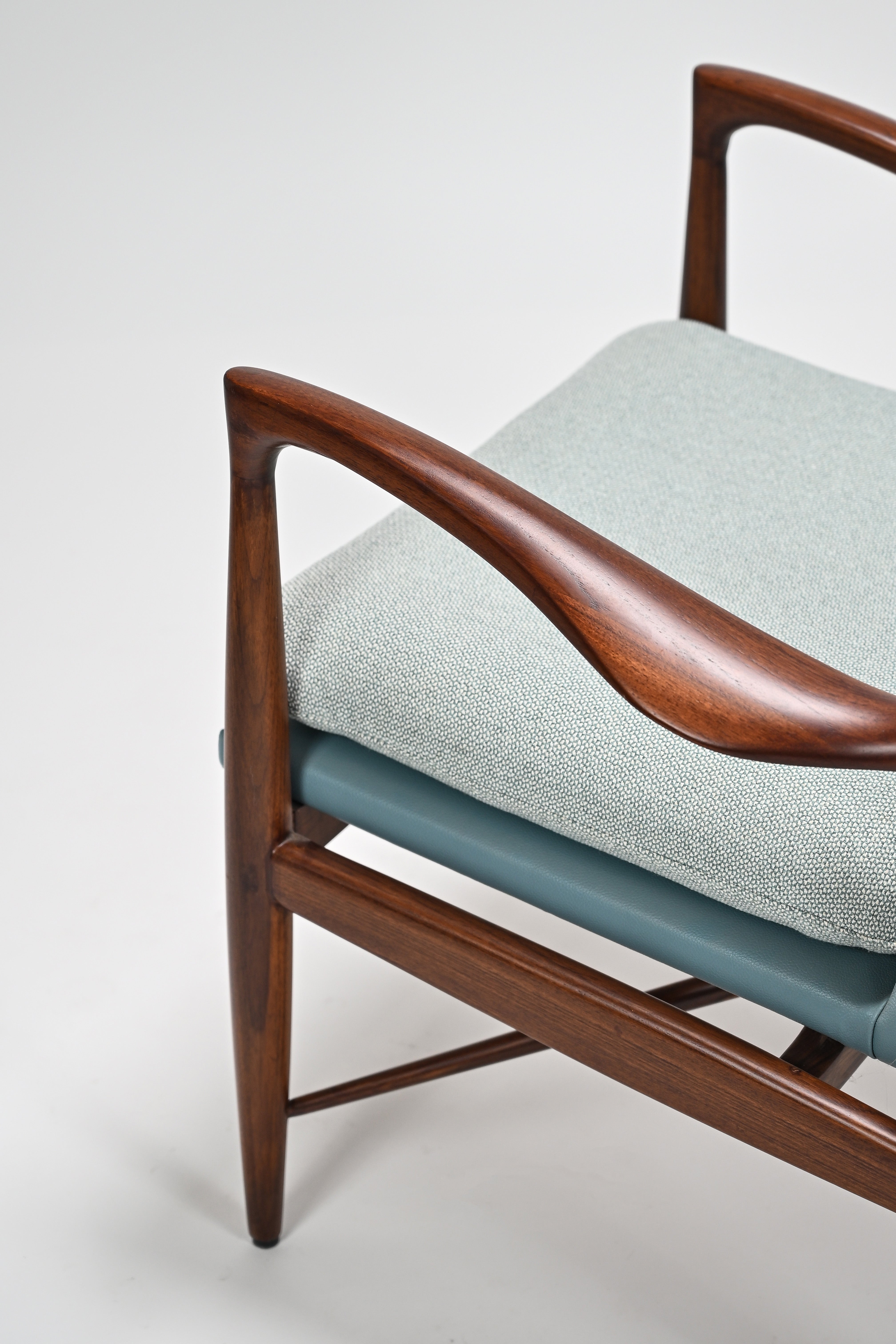Chair with wooden armrests and light blue cushion on a white background