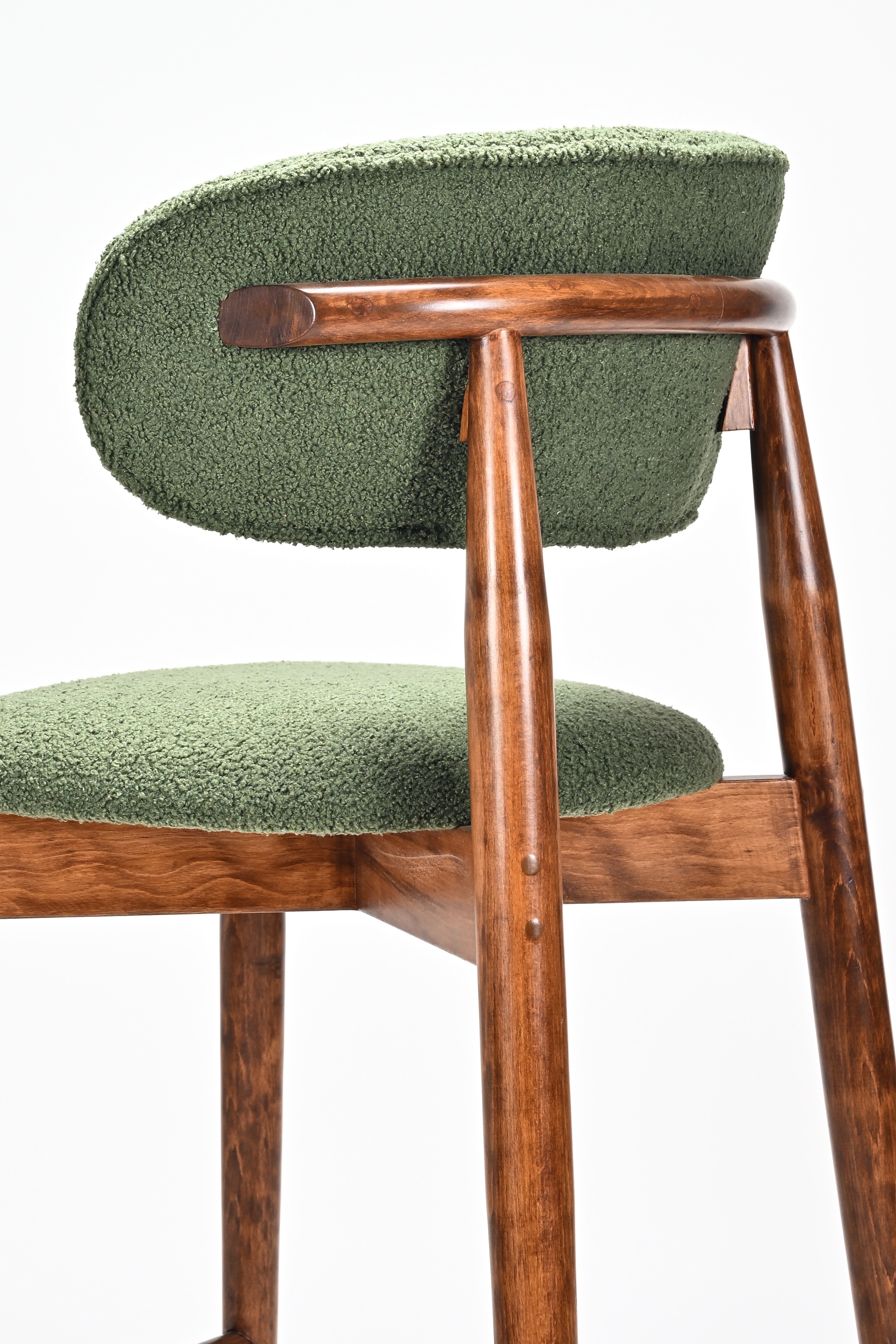 Green cushioned chair with wooden frame on a white background