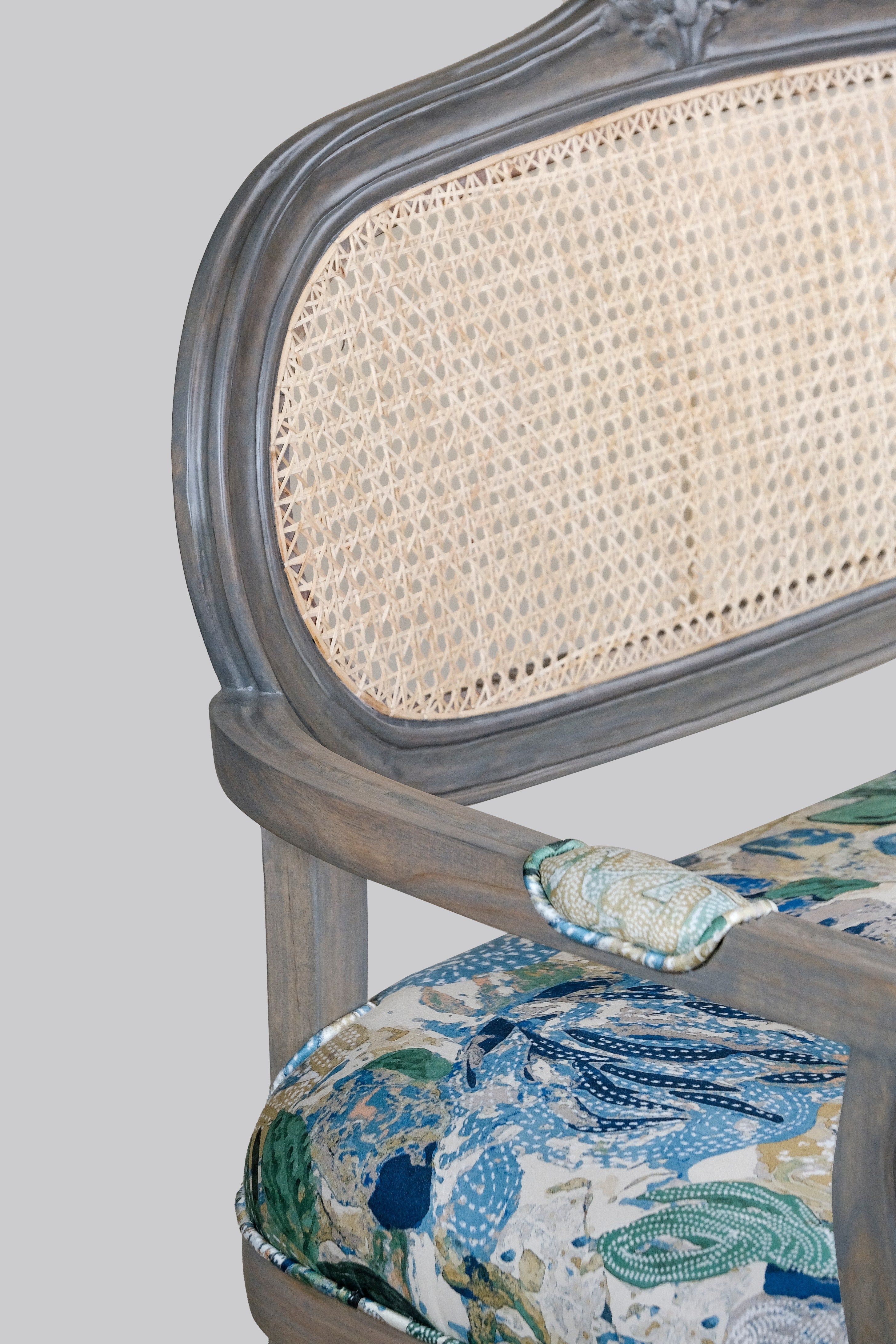 Chair with wicker backrest and patterned seat cushion on a plain background