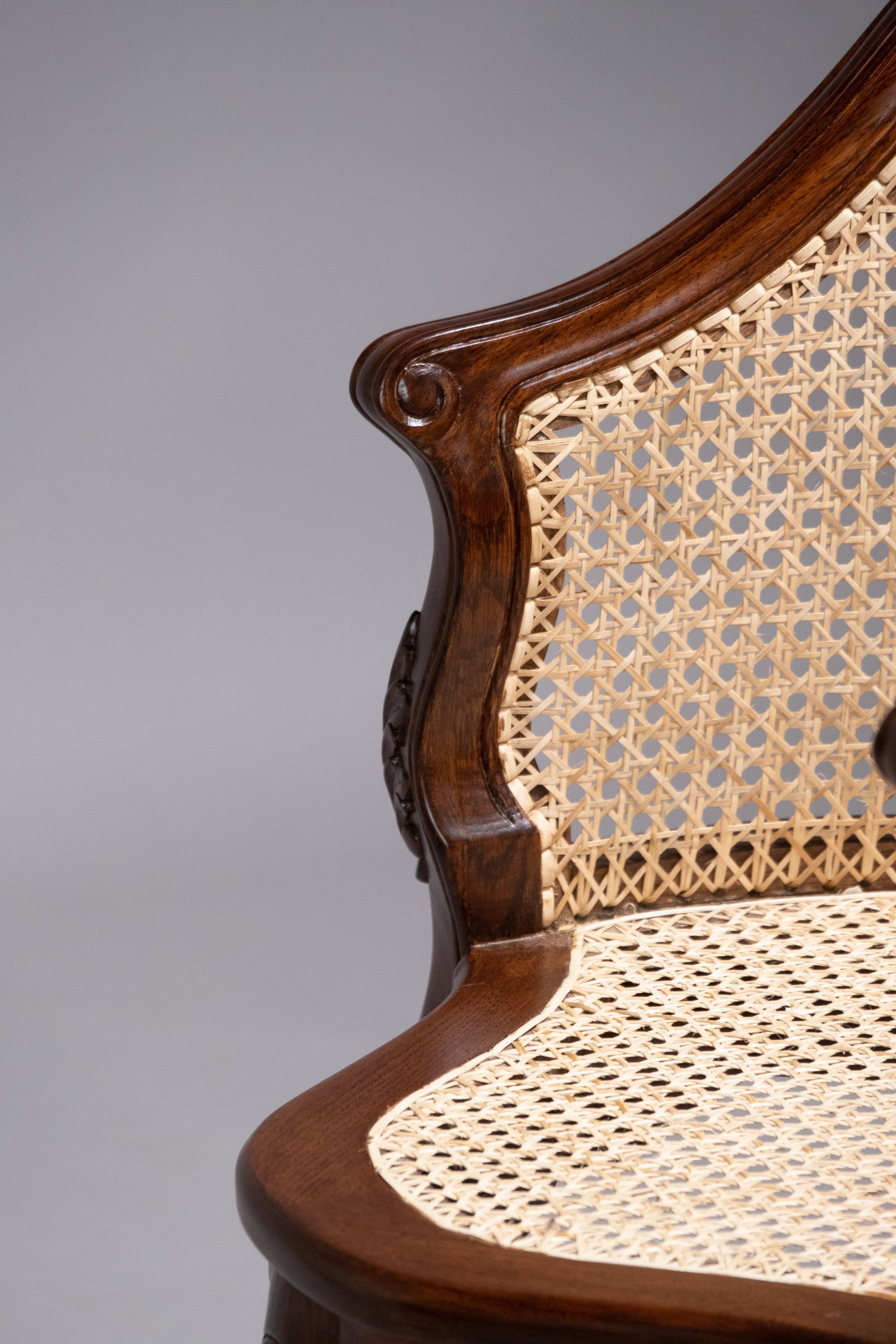 Close-up of a wooden chair with caned seat and backrest on a gray background