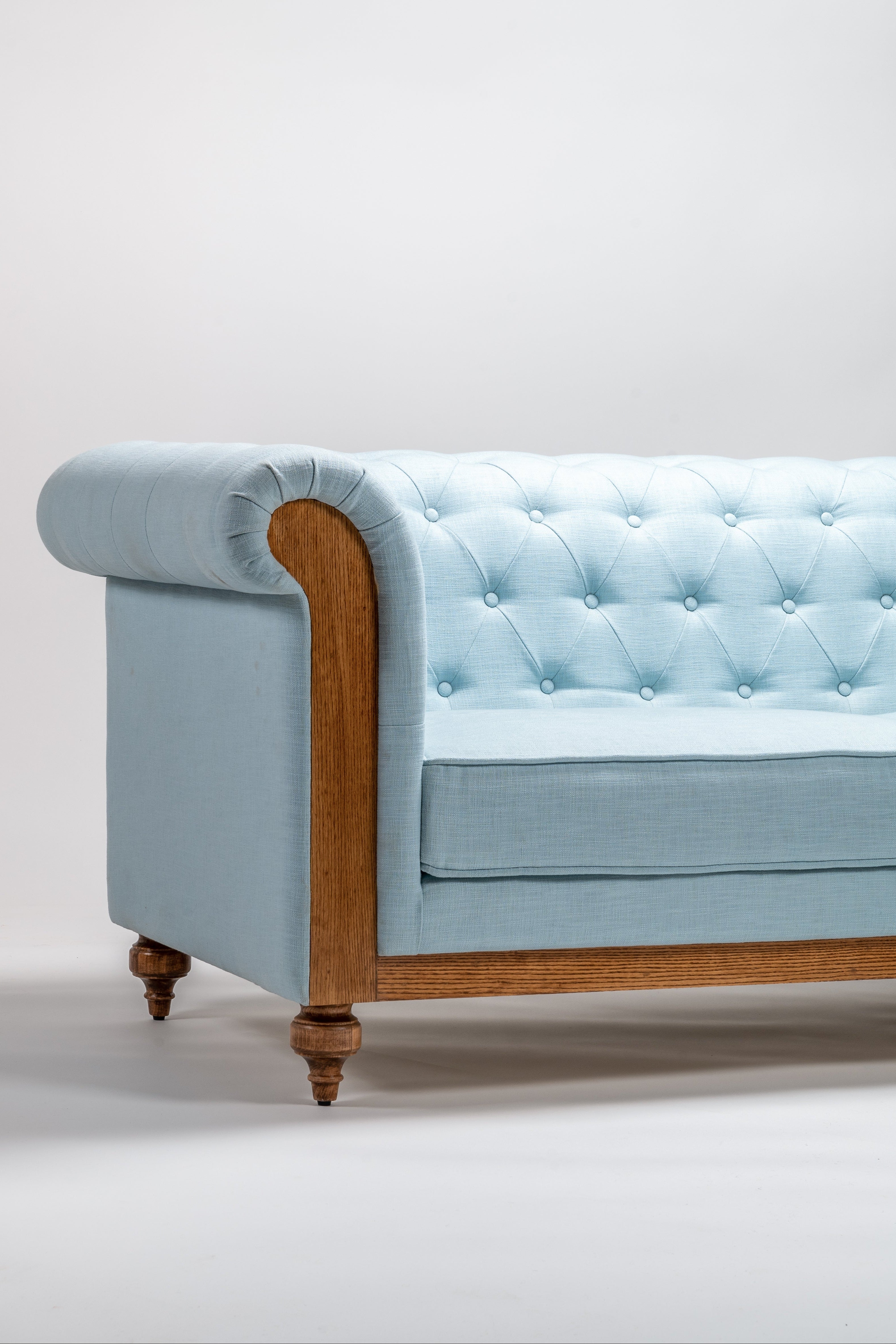 Light blue sofa with wooden armrests on a white background