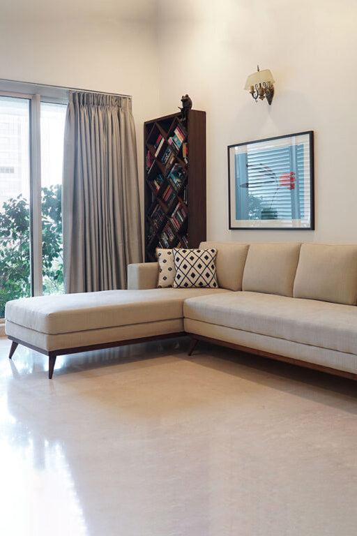 Beige sectional sofa in a living room with decorative pillows and framed pictures on the wall.