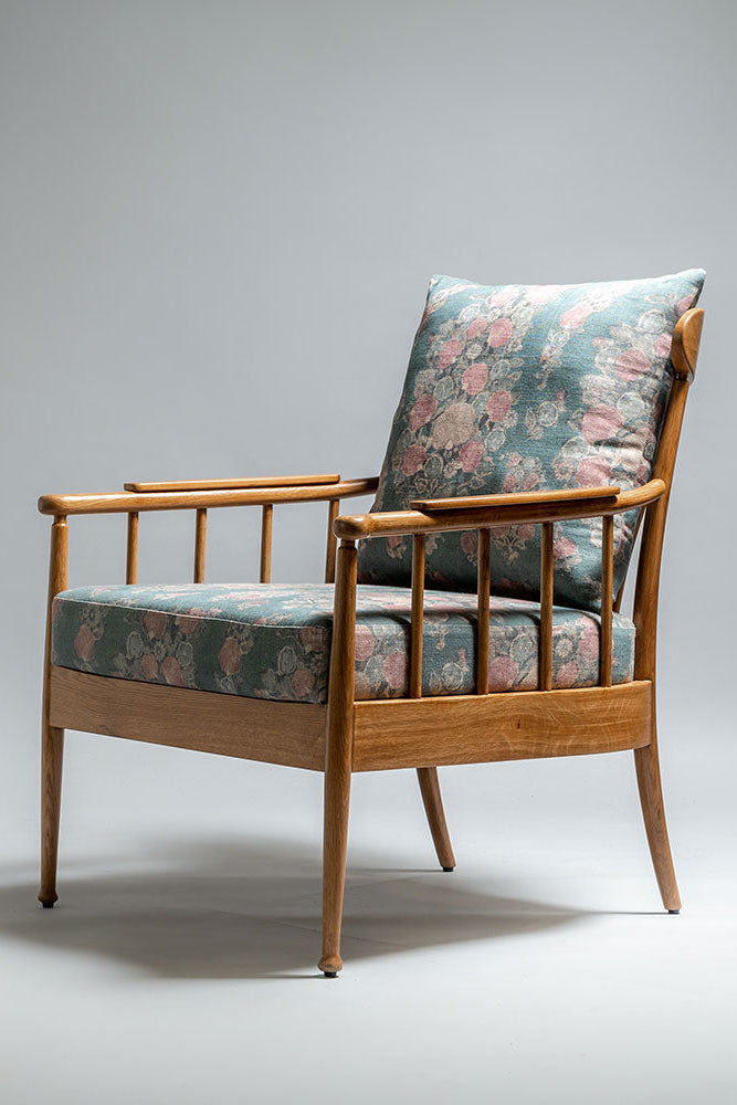 Wooden armchair with floral-patterned cushions on a gray background