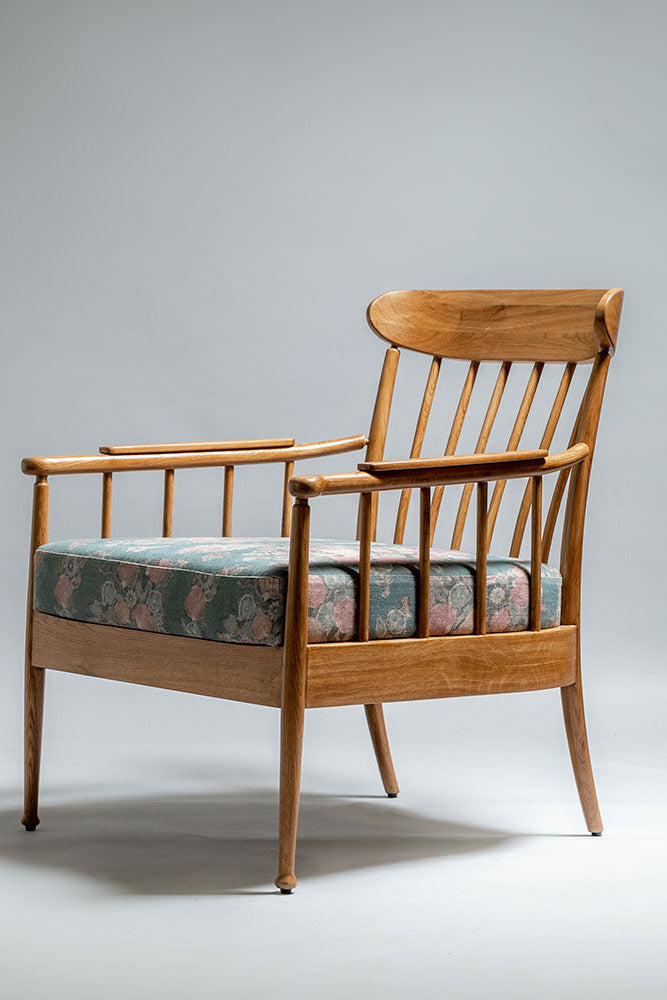 Wooden armchair with floral cushion on a gray background