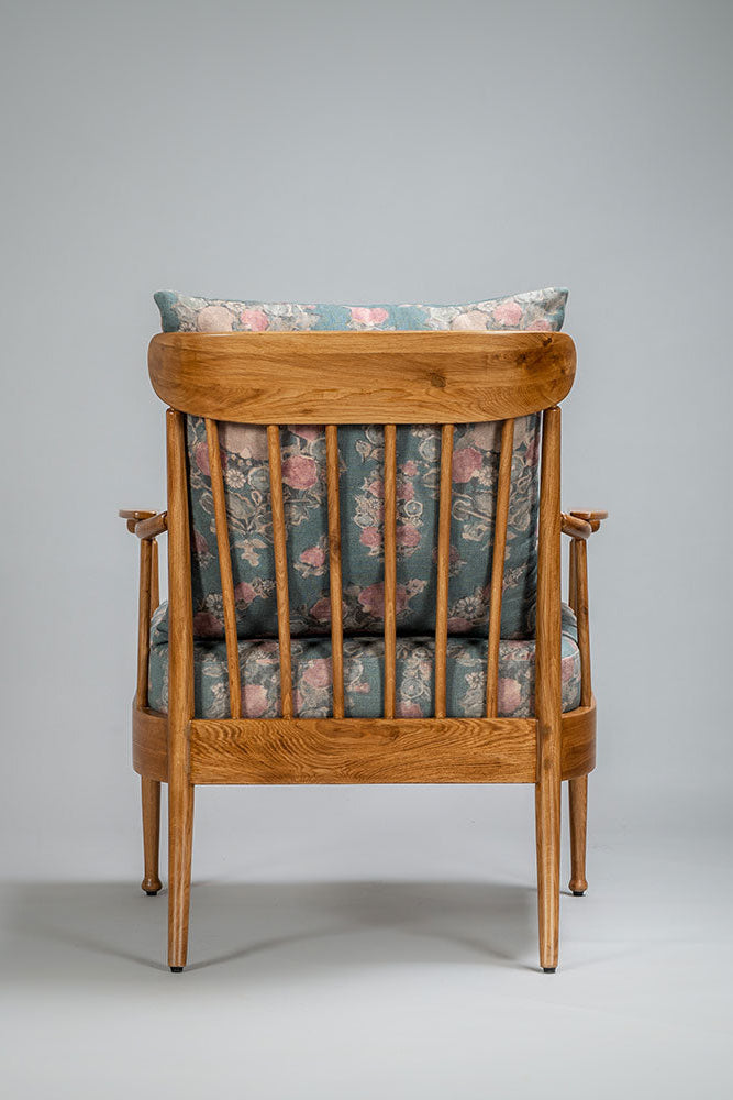 Wooden armchair with floral-patterned cushions on a gray background