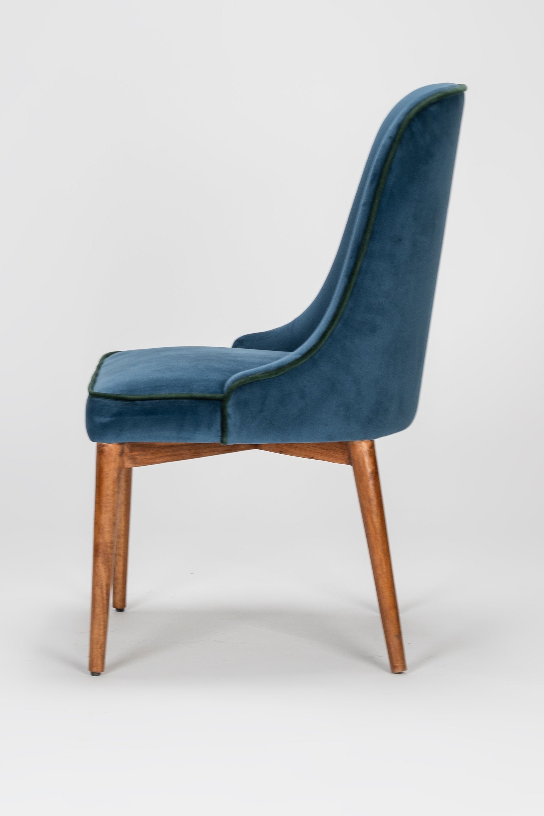 Blue velvet chair with wooden legs on a white background