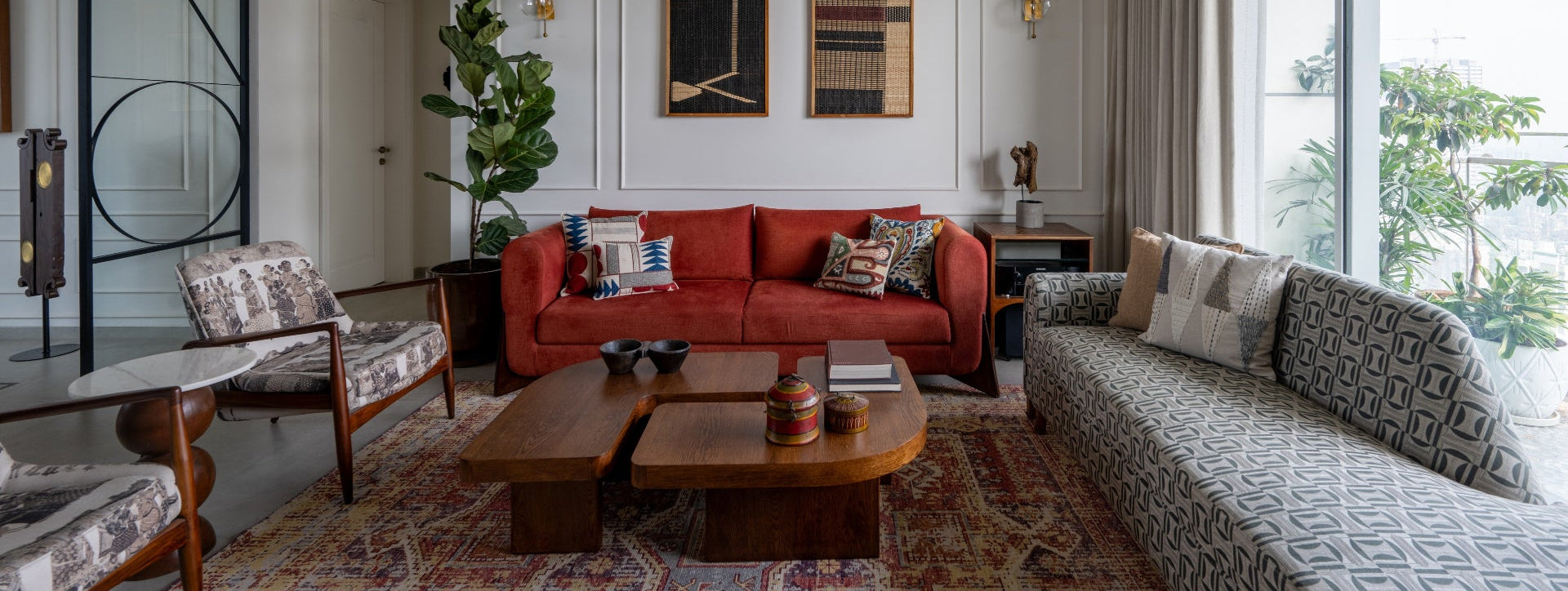 Living room with red sofa, patterned chairs, and large windows.