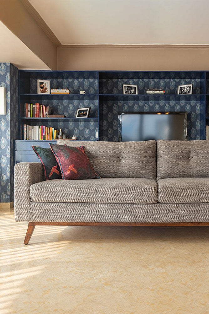 Gray sofa with decorative pillows in a living room setting with a bookshelf.