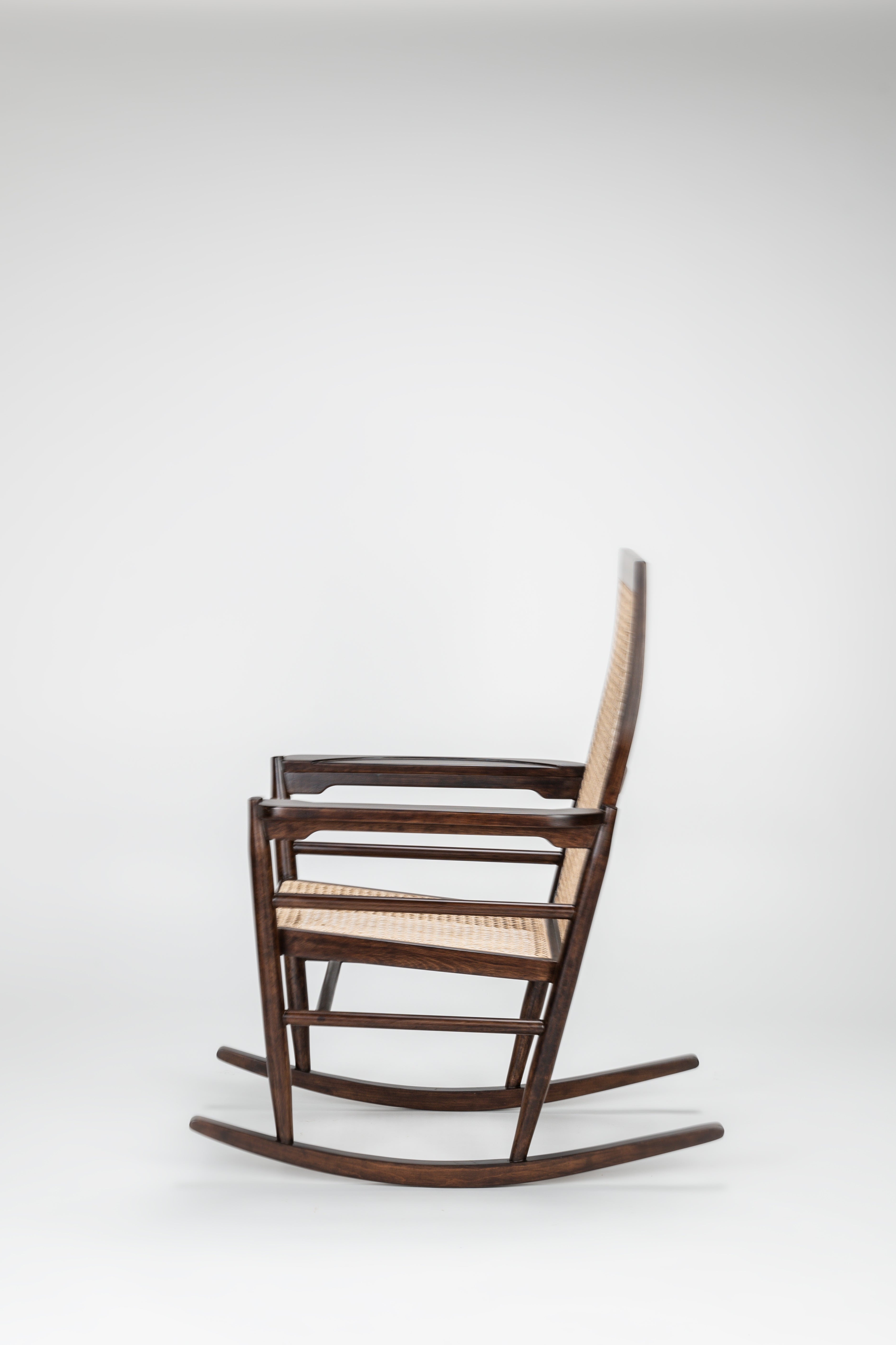 Wooden rocking chair with woven seat on a white background