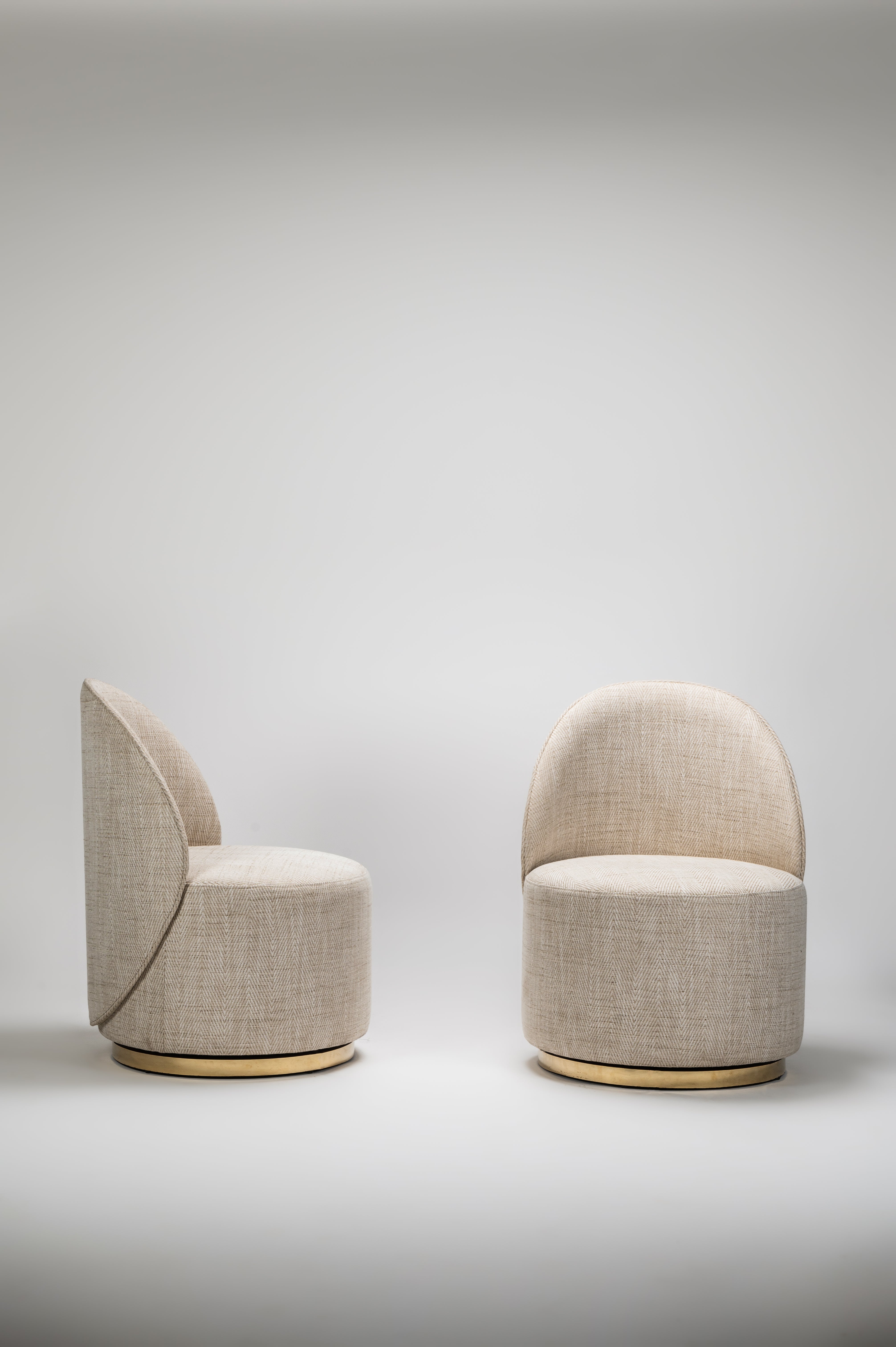Two beige chairs with gold accents on a light gray background