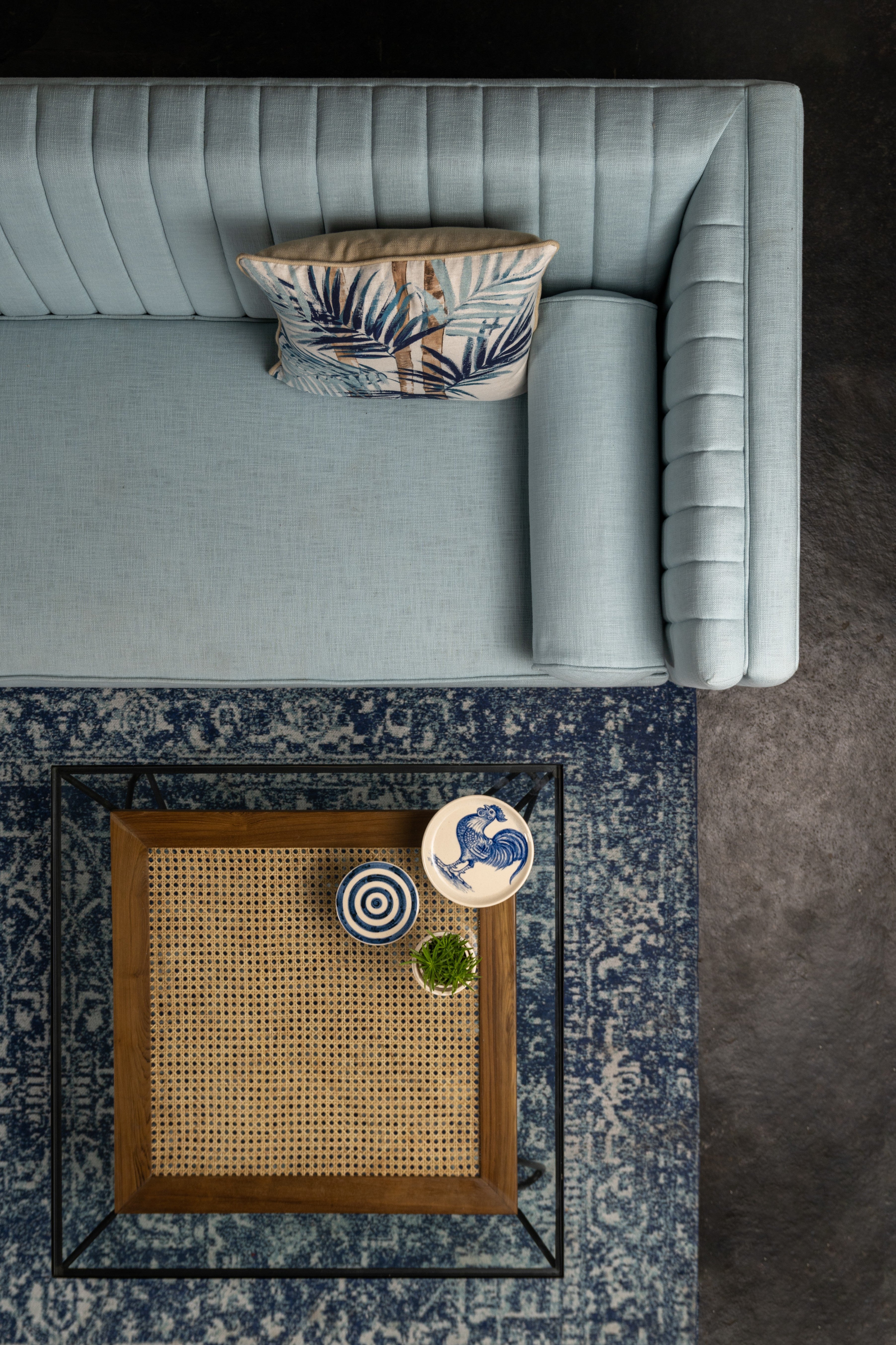 Light blue sofa with decorative pillows on a patterned rug
