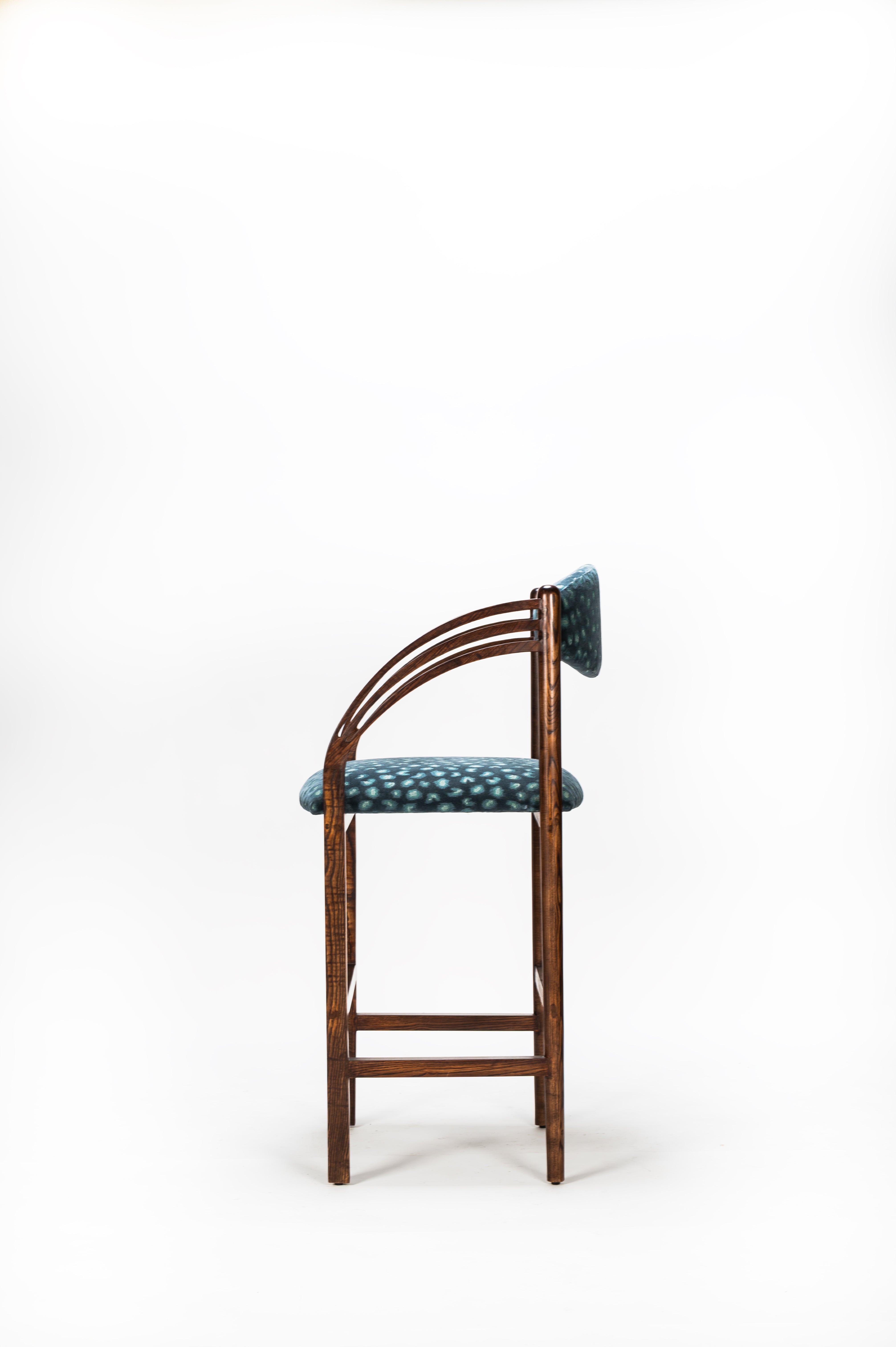 Wooden bar stool with a green cushioned seat on a white background